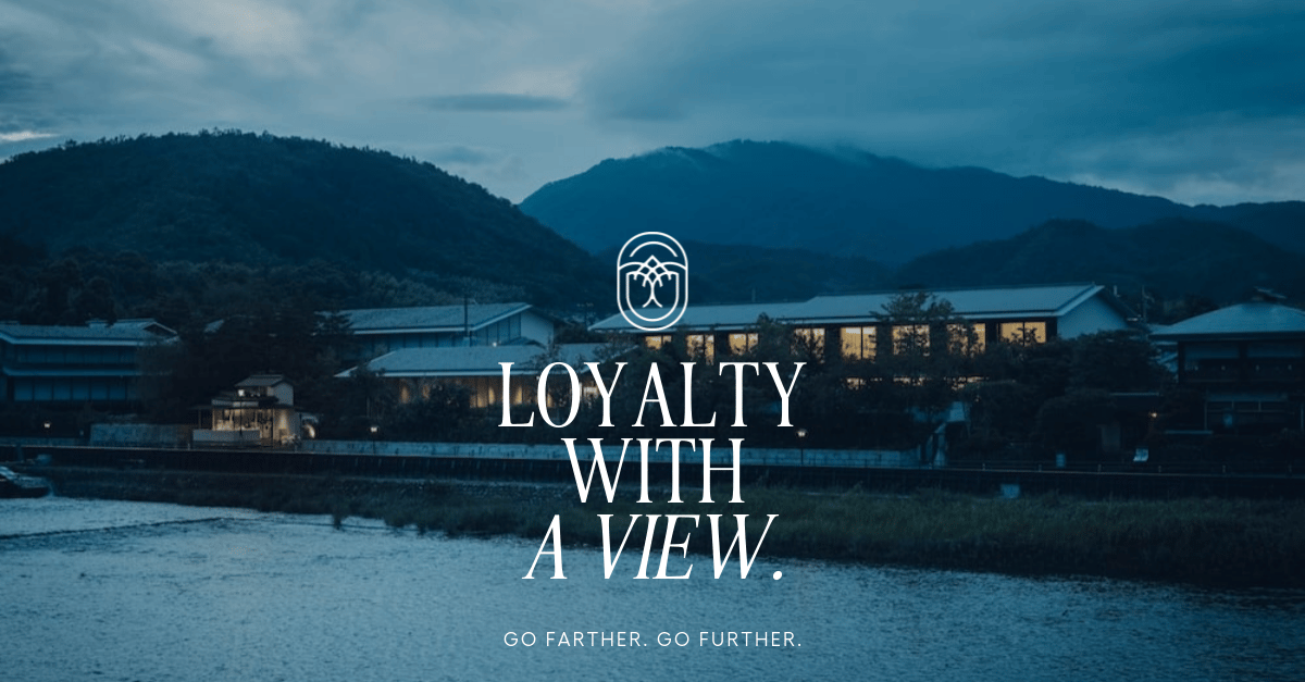 Traditional Japanese architecture nestled against misty mountains creates an intimate riverside sanctuary where modern luxury meets timeless tranquility at dusk.
