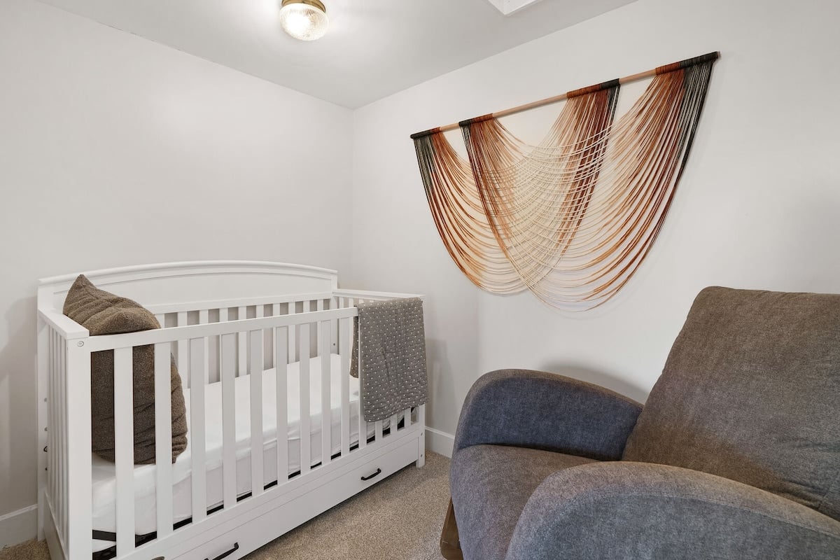 Bedroom 1 - Nursery room located through bedroom 1 with a crib and rocking chair.