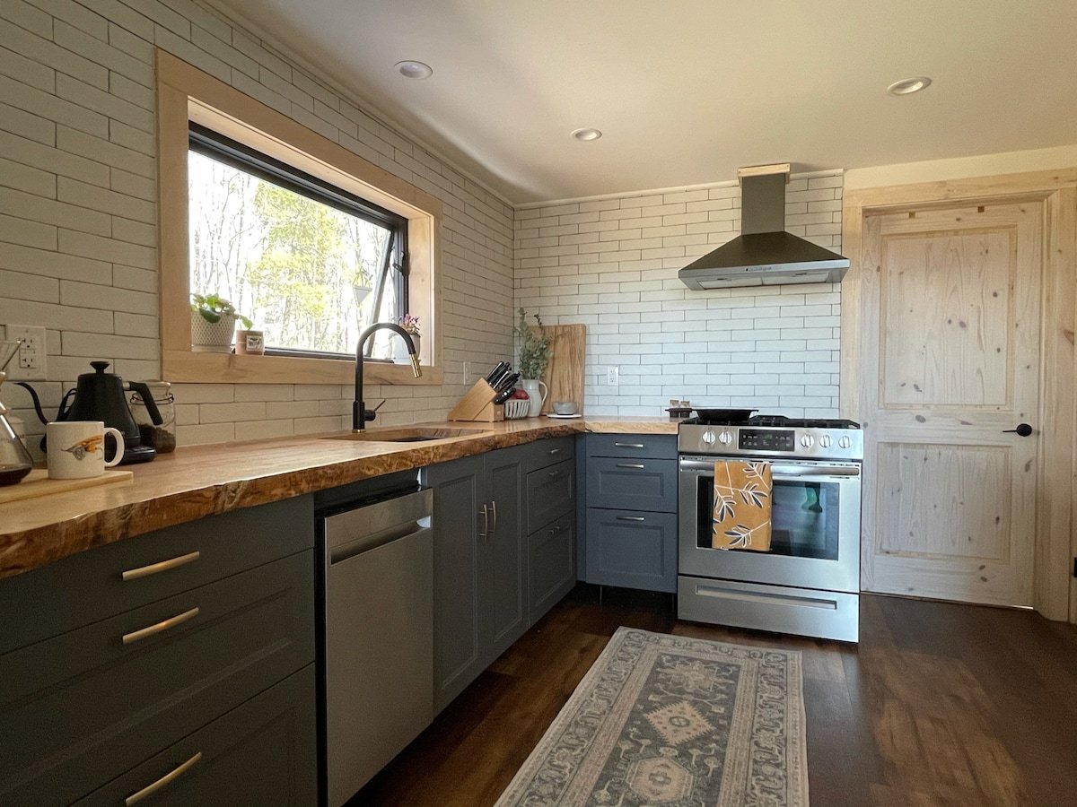 CAPTION: Nestled in Stamford, US, "Property" showcases a rustic modern architectural style with a warm and inviting atmosphere. The kitchen features sleek gray cabinetry contrasting beautifully with the natural wood countertops and accents. A soft color palette of earthy tones enhances the cozy vibe, while stainless steel appliances add a contemporary touch. Ideal for discerning travelers seeking a luxurious yet homely experience, this property promises style and comfort in a picturesque setting.