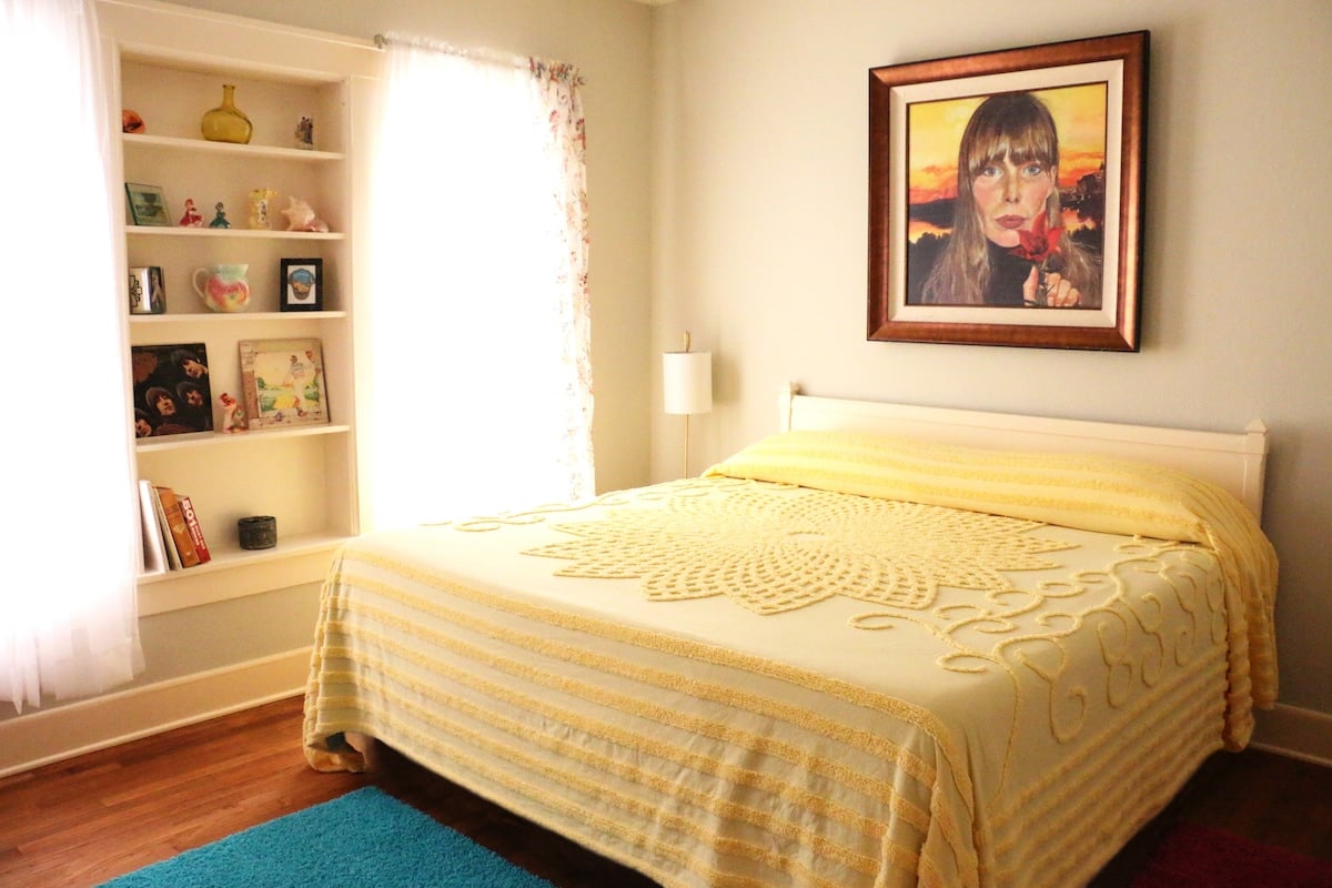 **CAPTION**: Discover "Property," a charming luxury retreat in Waco, US, showcasing a cozy traditional architectural style. The intimate atmosphere is accentuated by warm yellow hues and eclectic artwork that evoke a sense of homey relaxation. Natural light floods through sheer curtains, illuminating the elegant bedroom with wood floors and built-in shelves filled with delicate trinkets. Perfect for travelers seeking a quaint yet sophisticated escape in Texas.