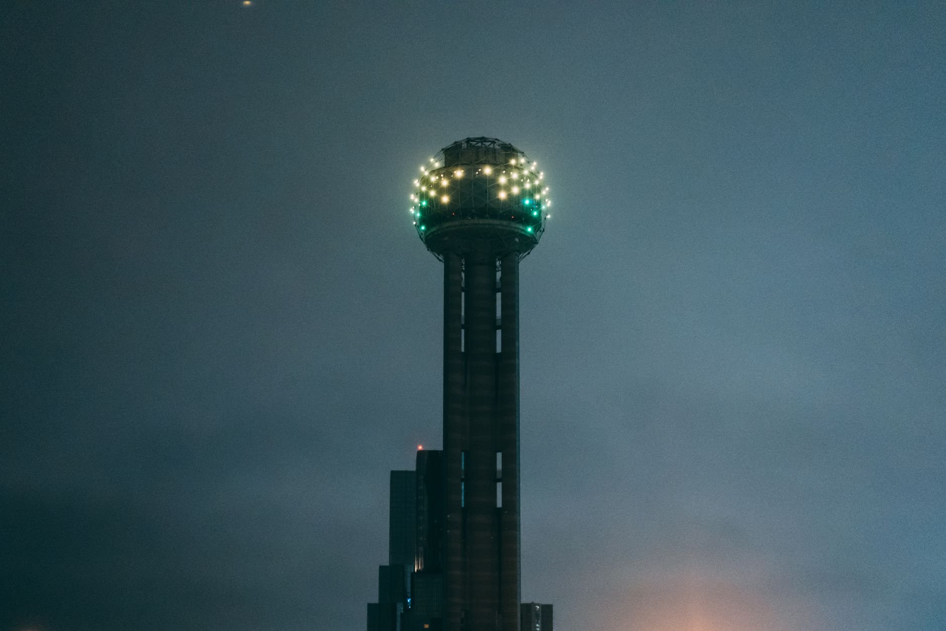 The iconic Reunion Tower glowing vividly during the night in Dallas, Texas.