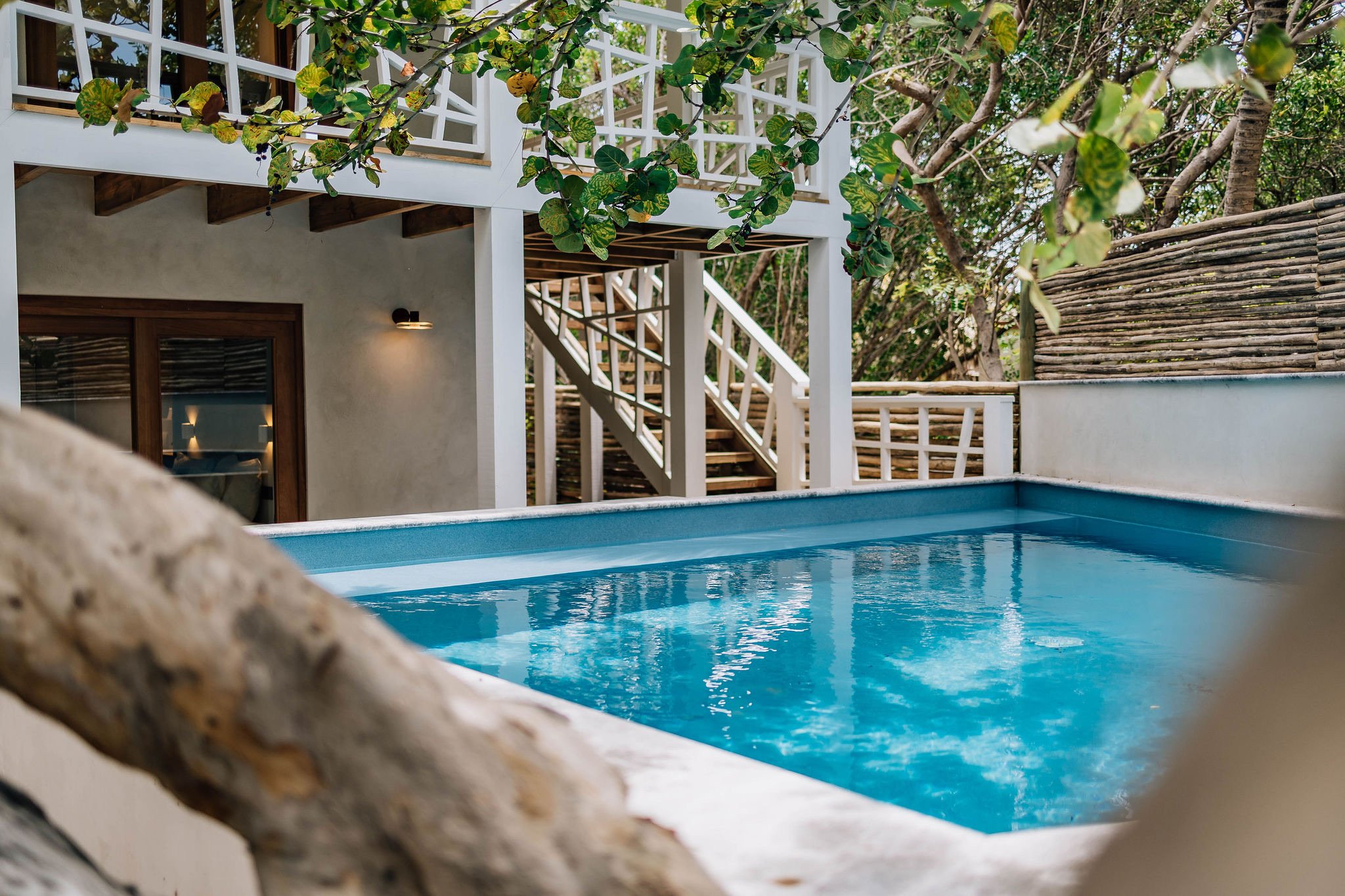 Crystalline waters mirror tropical canopy while weathered stone frames this intimate plunge pool, where white railings and natural textures create perfect Caribbean sanctuary.