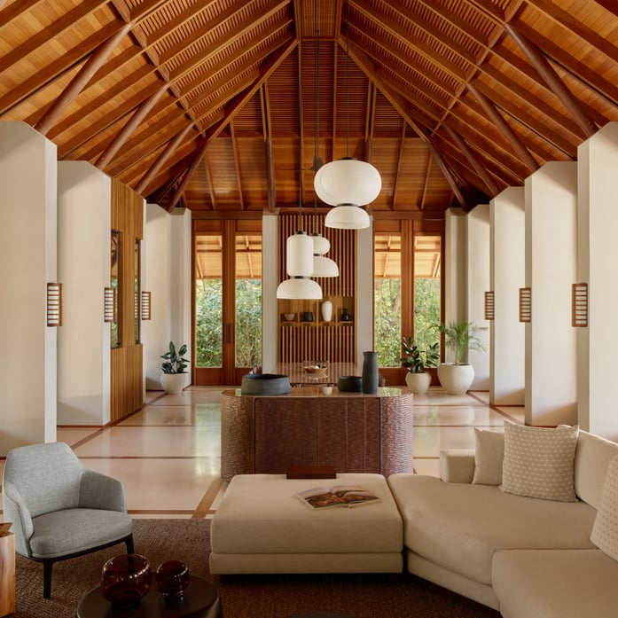 Soaring timber beams frame this cathedral-like pavilion where polished stone floors reflect tropical light filtering through louvered windows, creating an atmosphere of serene sophistication.