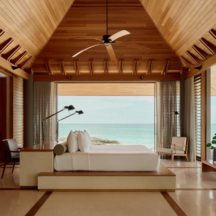 Warm teak beams frame an ocean vista from this elevated pavilion, where Caribbean trade winds drift through louvered walls and polished floors reflect endless blue.