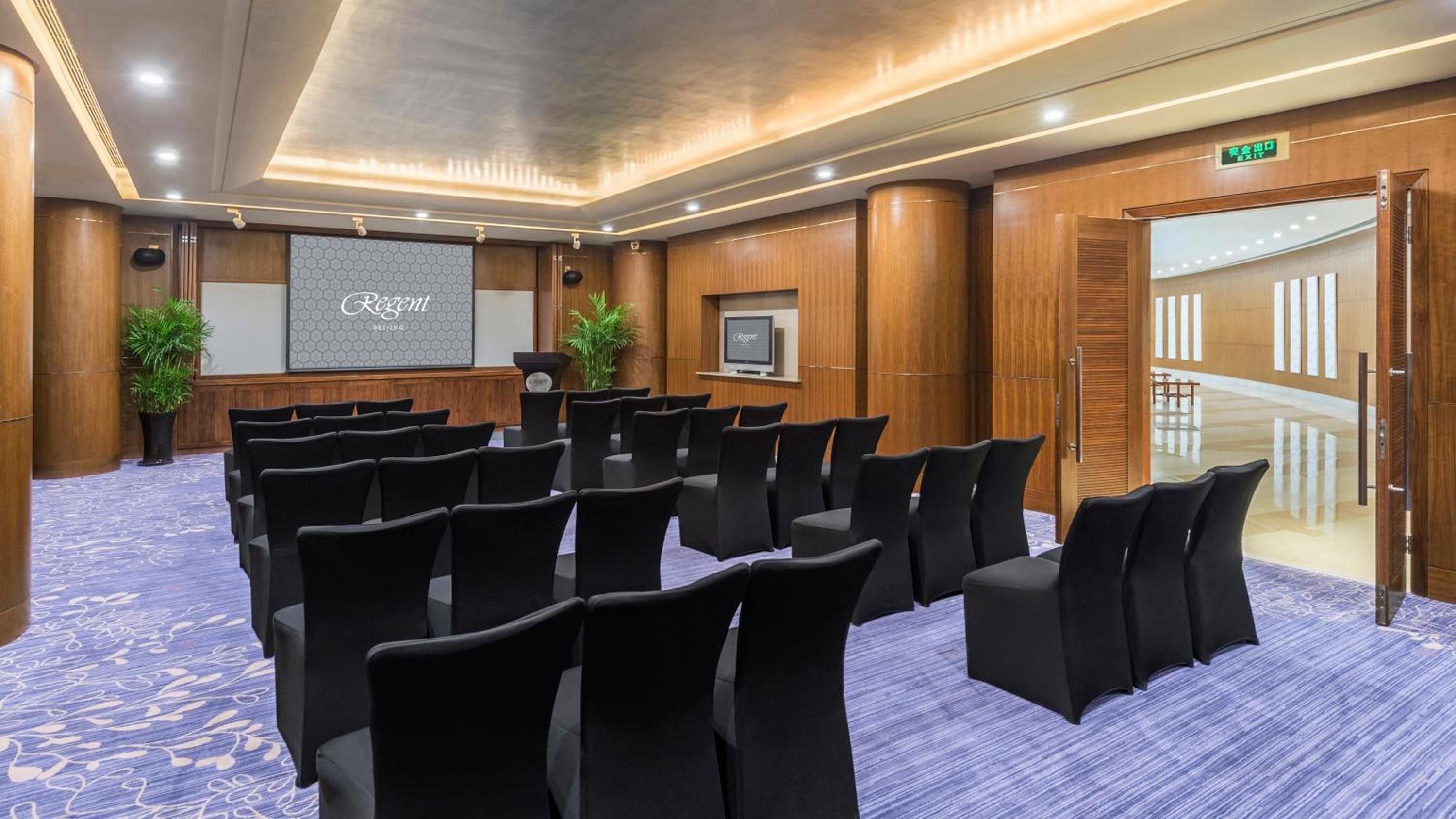 Rich wood paneling and sophisticated purple carpeting create an intimate boardroom atmosphere where business conversations unfold beneath warm recessed lighting and elegant architectural details.