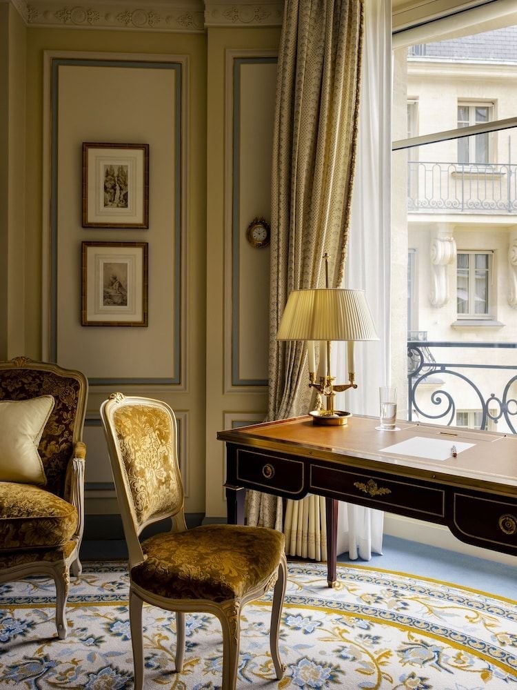 Golden damask chairs and an ebony writing desk create an intimate corner where Parisian light filters through silk curtains, framing classical elegance.