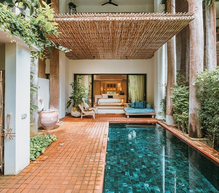 Warm terracotta tiles lead to an intimate plunge pool beneath woven bamboo ceilings, where jade-tiled waters reflect the serene bedroom beyond.