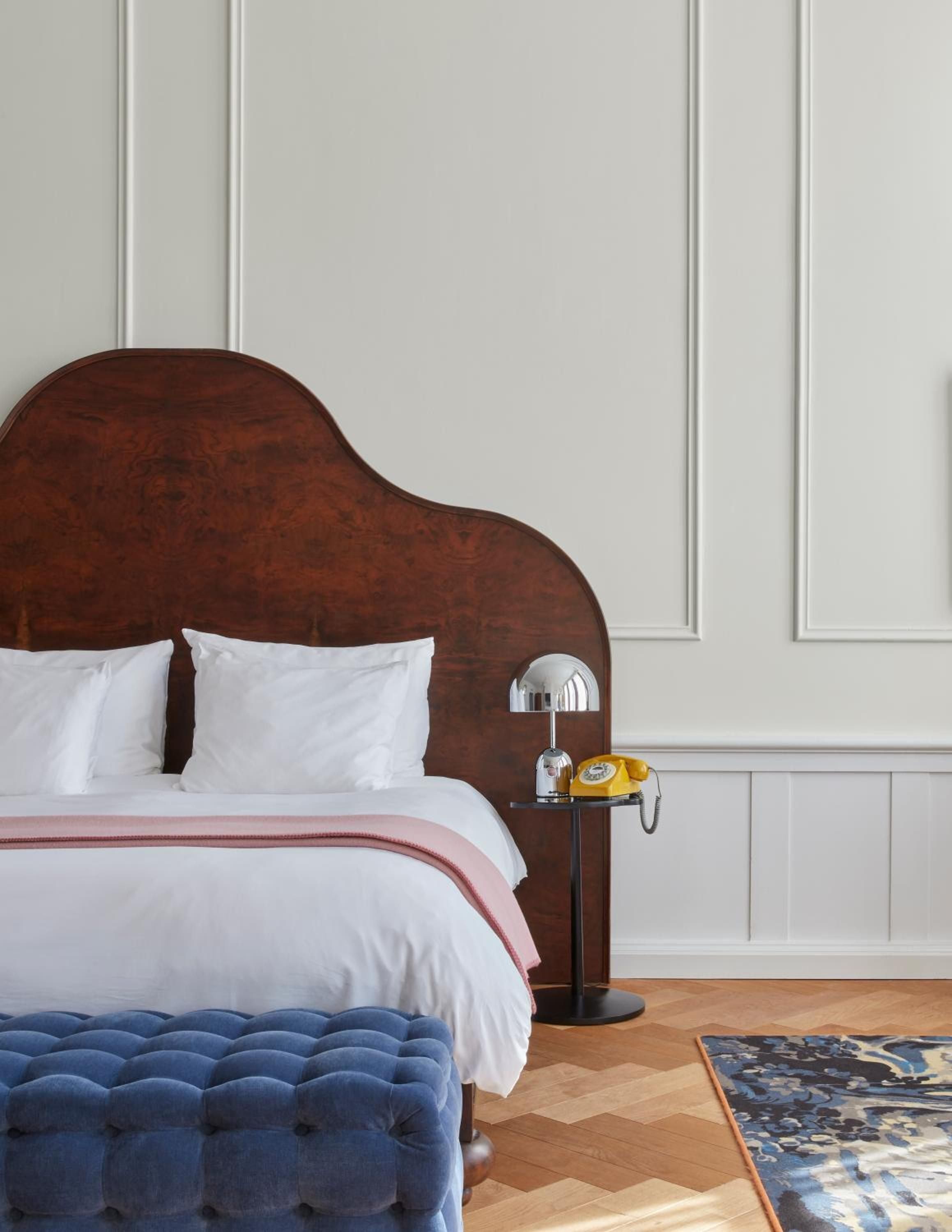 Rich walnut headboards and crisp linens create intimate sanctuaries, while vintage yellow rotary phones add nostalgic charm to thoughtfully curated canal house suites.