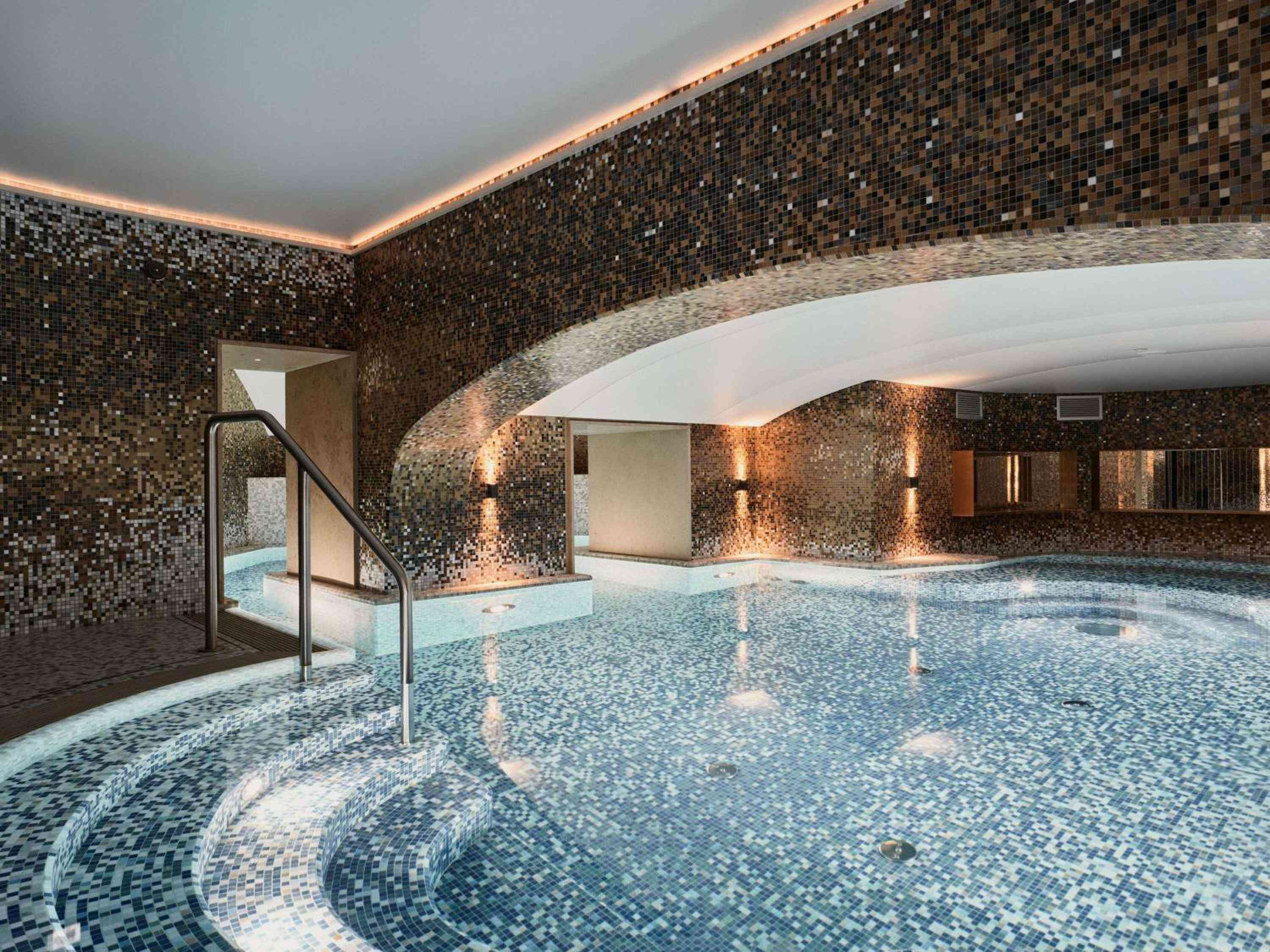 Mosaic tiles shimmer in warm amber light as this subterranean pool sanctuary beckons with curved archways and tranquil waters reflecting centuries-old European elegance.