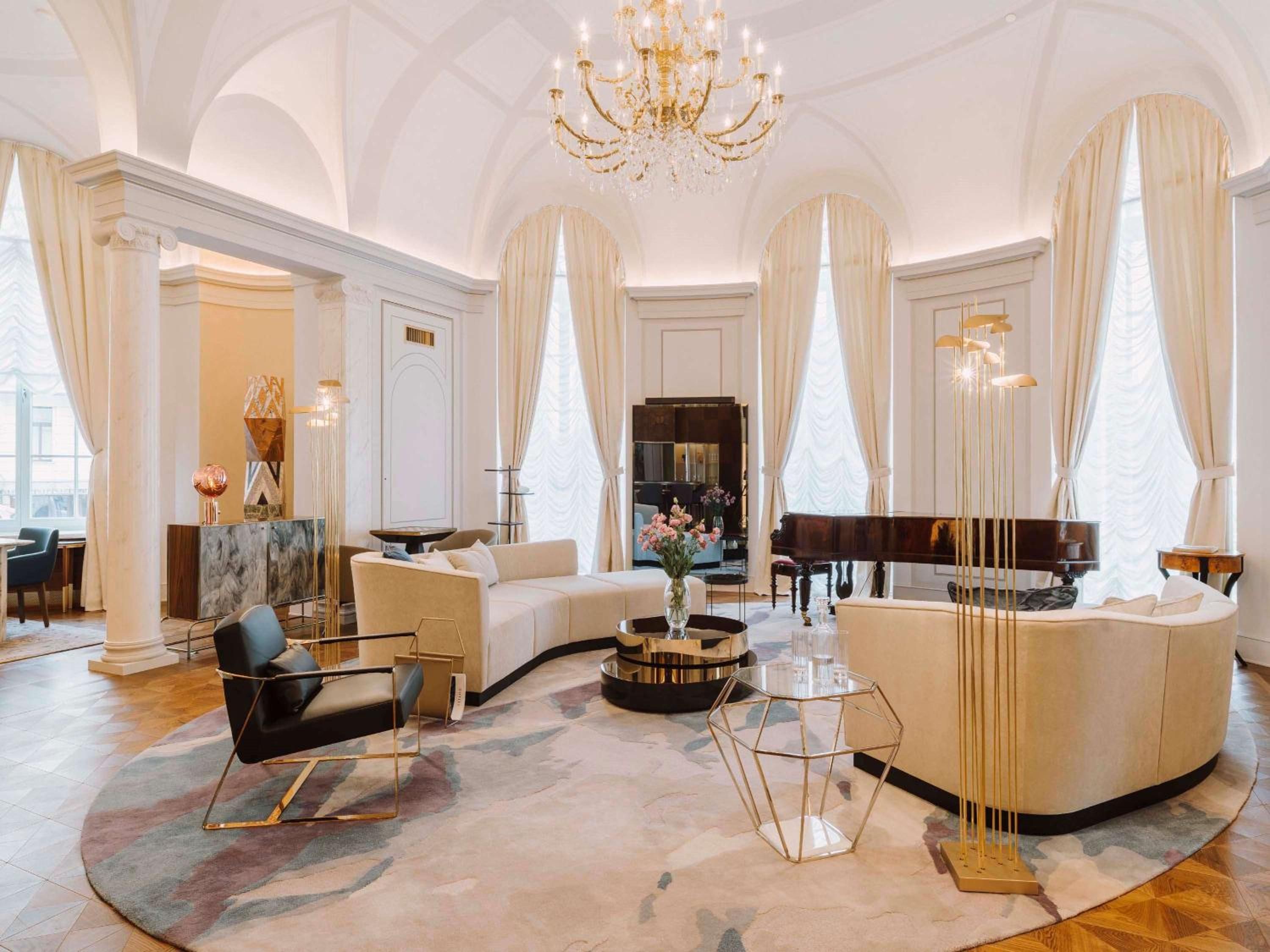 Soaring arched ceilings and a gleaming crystal chandelier frame this palatial lounge, where honey-toned velvet seating and geometric marble floors create timeless Warsaw elegance.