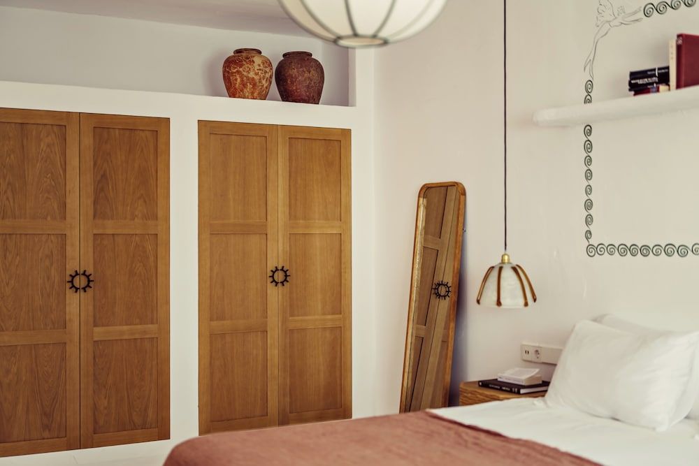 Warm oak wardrobes with star-shaped pulls frame the sleeping alcove, where brass pendant lights cast intimate pools of light over crisp white linens.