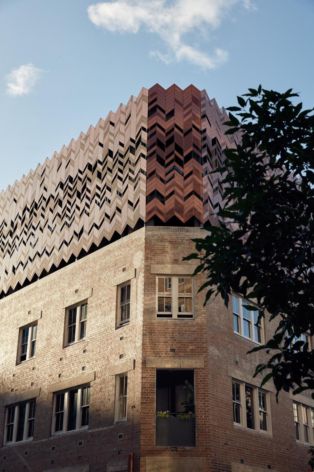 Striking chevron brickwork creates a dramatic geometric facade, where traditional masonry meets bold contemporary design in this architectural masterpiece rising against Sydney's sky.