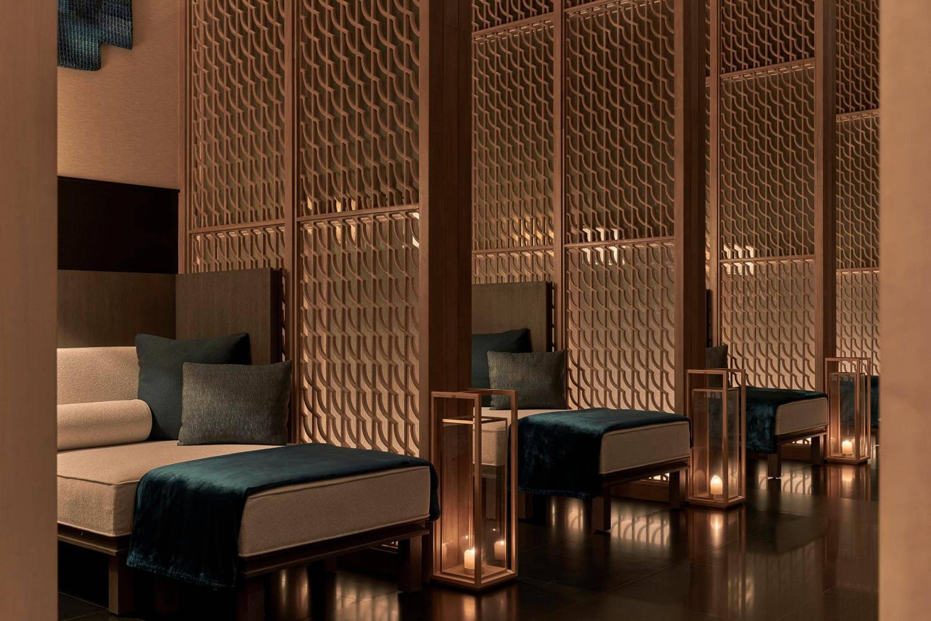 Copper-toned lattice screens create intimate alcoves in the spa's relaxation lounge, where warm candlelight dances across geometric patterns and plush daybeds invite complete tranquility.