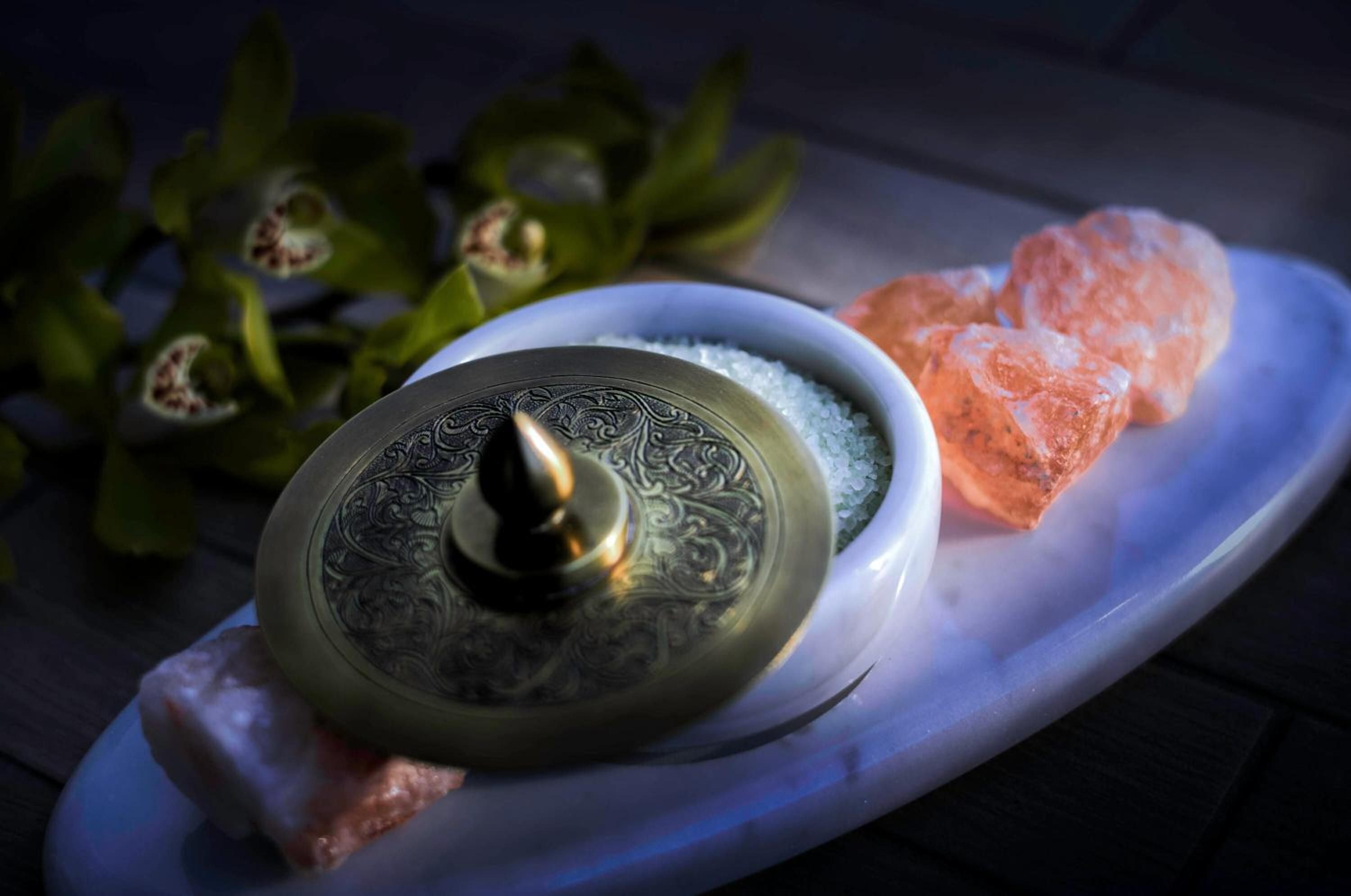Himalayan salt crystals and ornate brass vessels create an intimate ritual space where ancient wellness traditions meet contemporary luxury at this serene spa sanctuary.