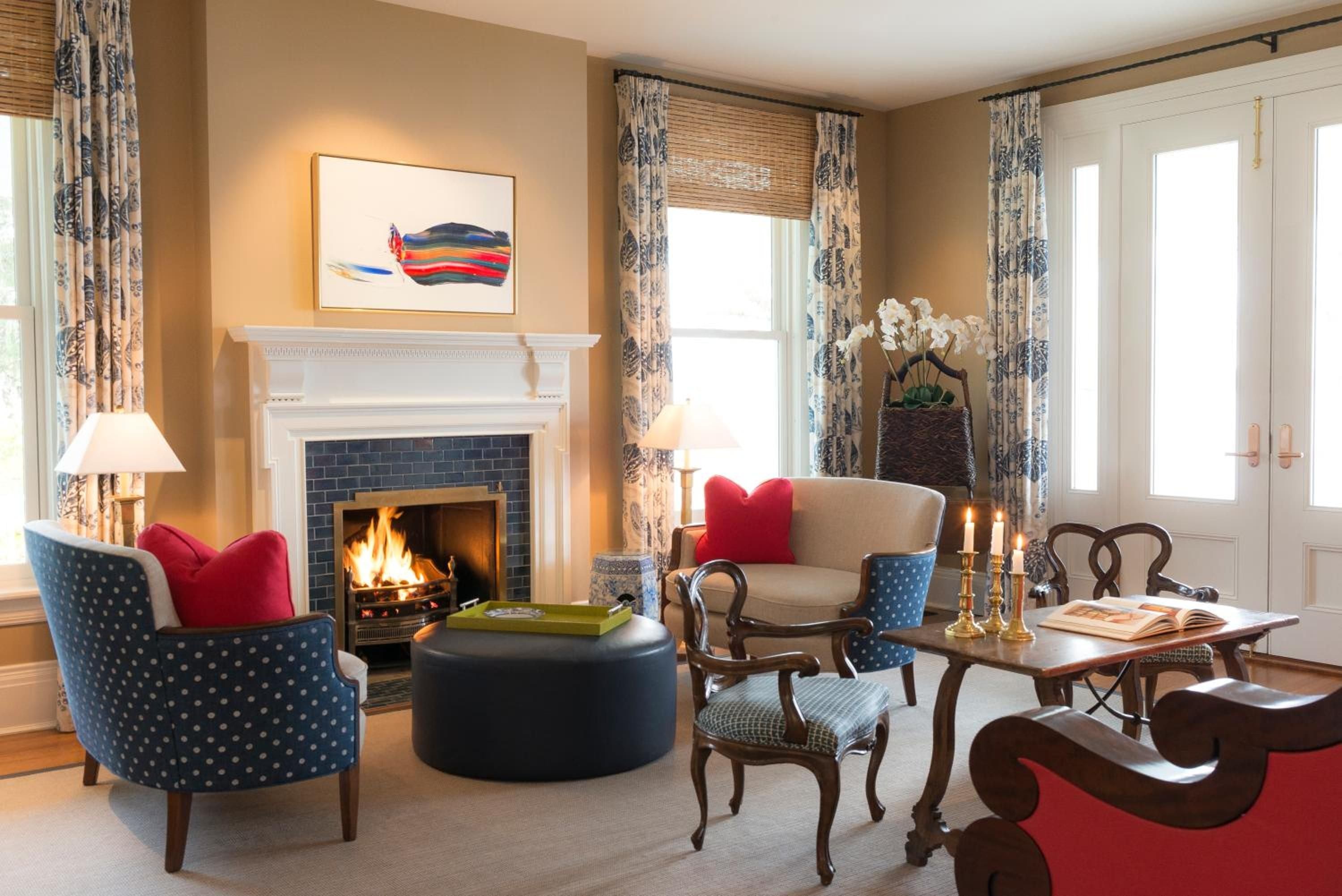 Crackling flames illuminate this intimate sitting room where navy polka-dot armchairs and red velvet pillows create a sophisticated nautical tableau against honey-toned walls.