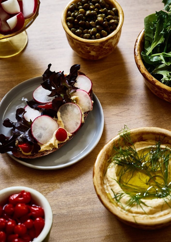 Artisanal spreads and house-pickled vegetables create an intimate mezze moment, where locally-sourced radishes and herb-infused oils invite unhurried conversation over wooden bowls.