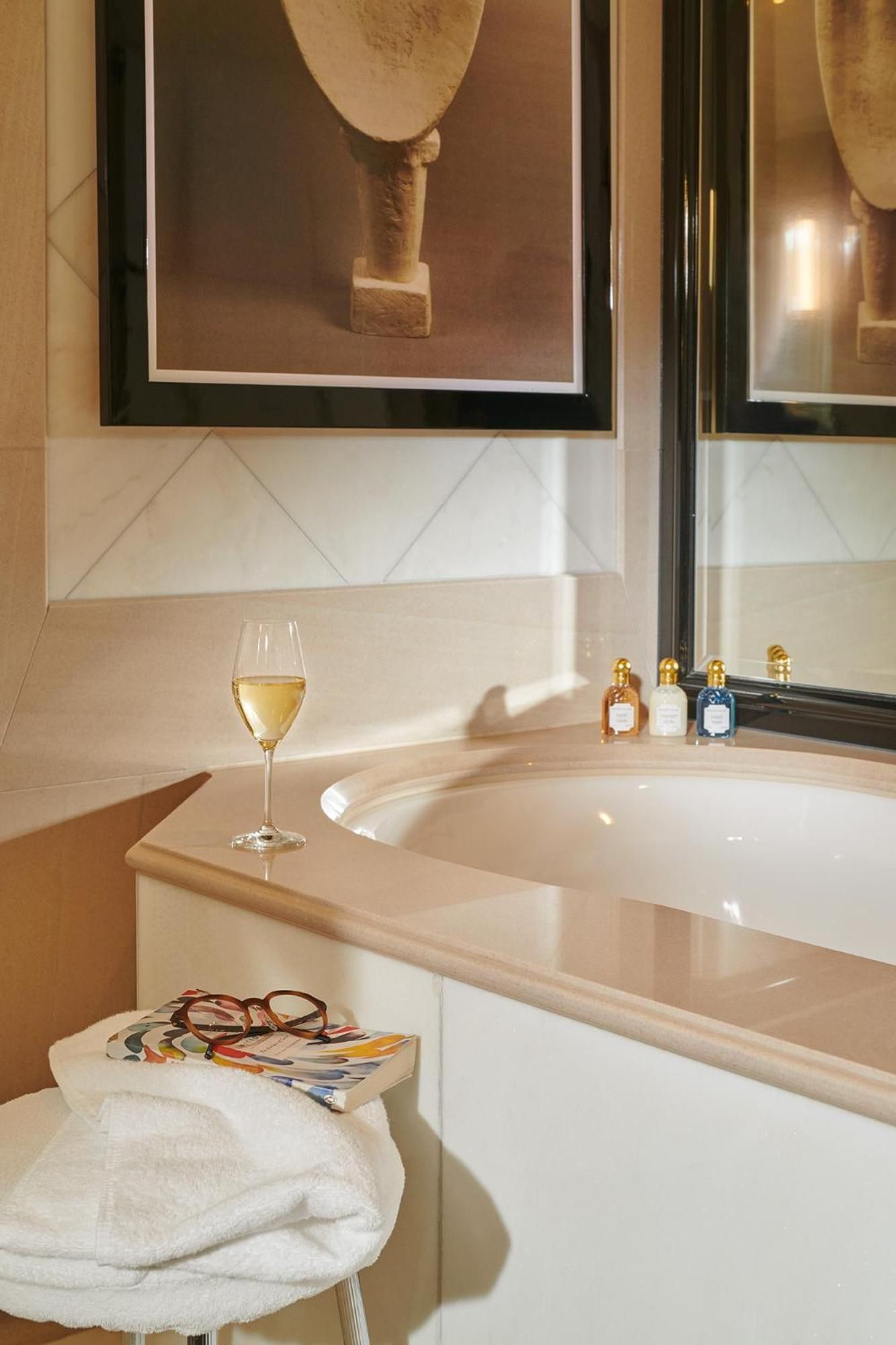 Marble surrounds and golden fixtures create a spa-like sanctuary where champagne and reading materials transform bathing into pure indulgence.