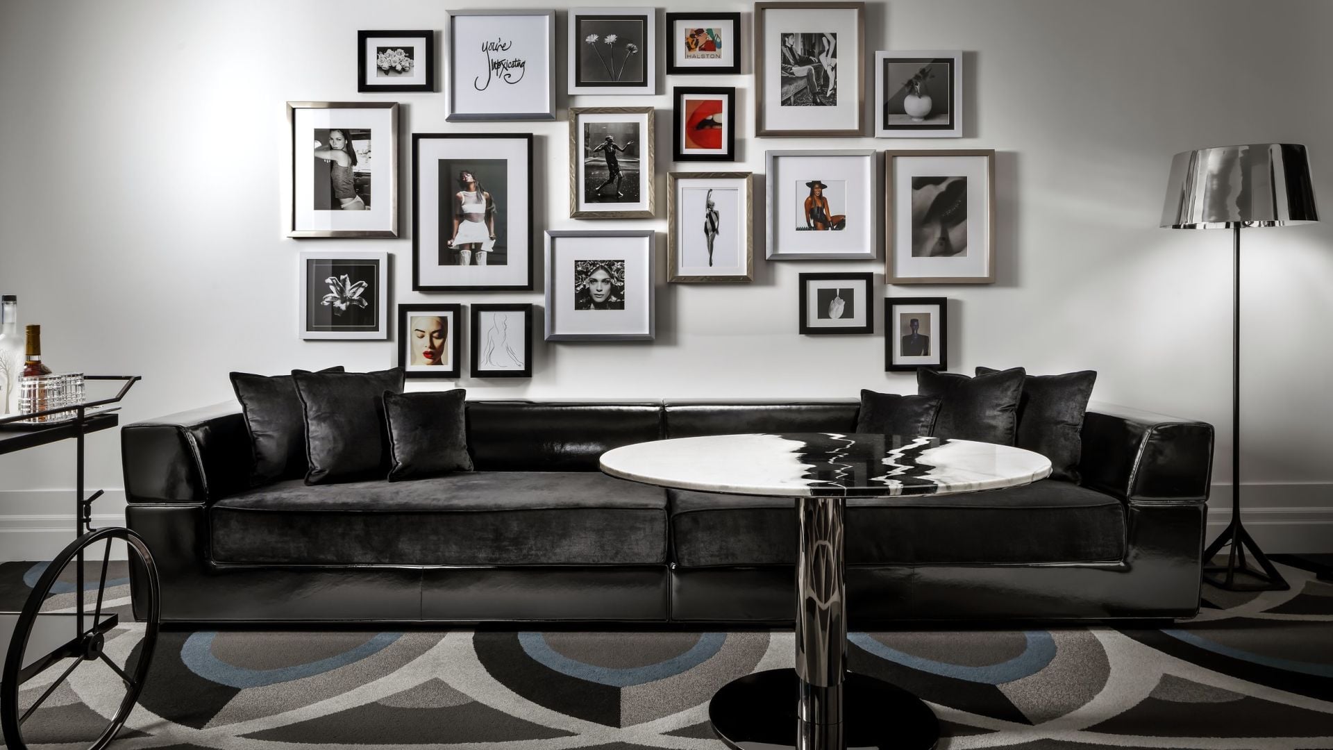 Monochromatic sophistication defines this lounge area, where black leather seating anchors an impressive gallery wall of framed photography and contemporary art.