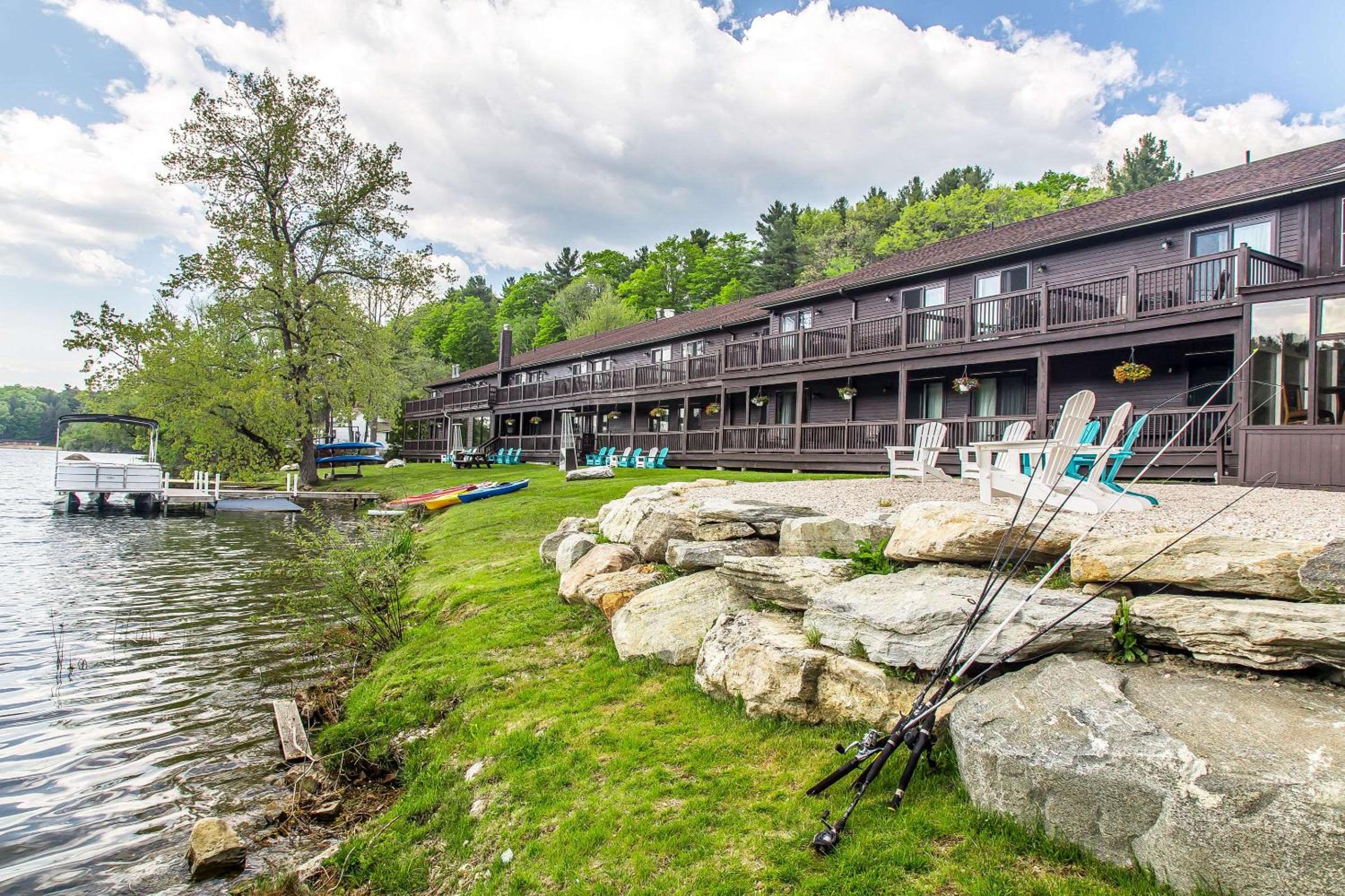 Adirondack chairs dot the stone-lined shoreline where fishing rods stand ready and kayaks await launching into the mirror-calm waters of this mountain lake retreat.
