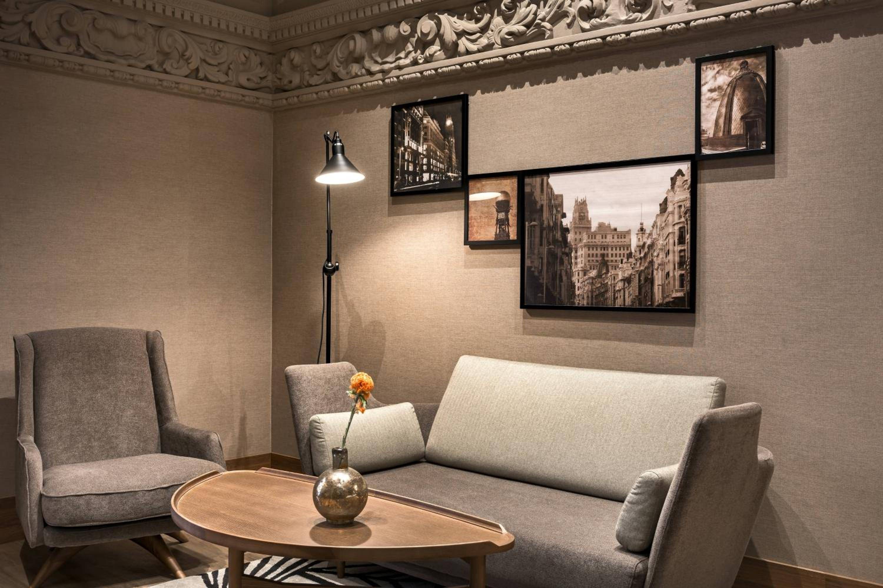 Ornate moldings crown this intimate seating area where vintage European photographs and warm lamplight create an elegant sanctuary for quiet conversation.