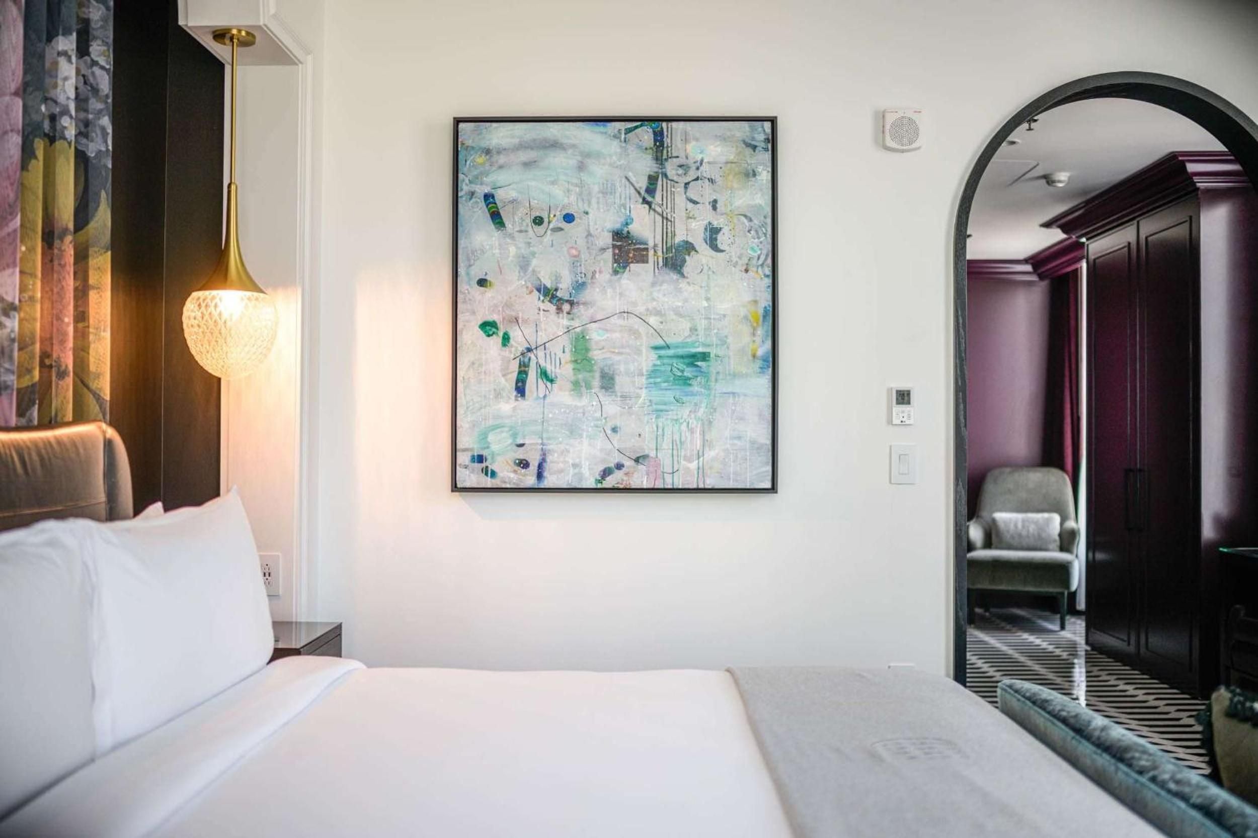 Warm brass pendant lighting and abstract artwork create an intimate retreat, while the archway glimpse into rich mahogany-paneled spaces hints at timeless sophistication.