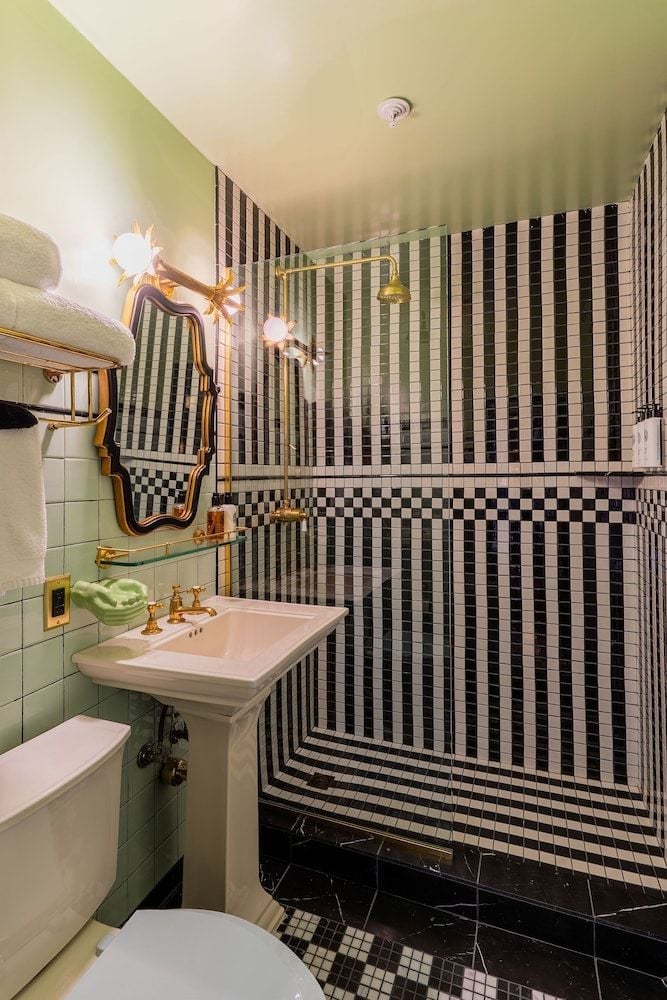 Bold black and white striped tiles create a dizzying optical illusion in this compact powder room, where brass fixtures and vintage sconces add old-world glamour.