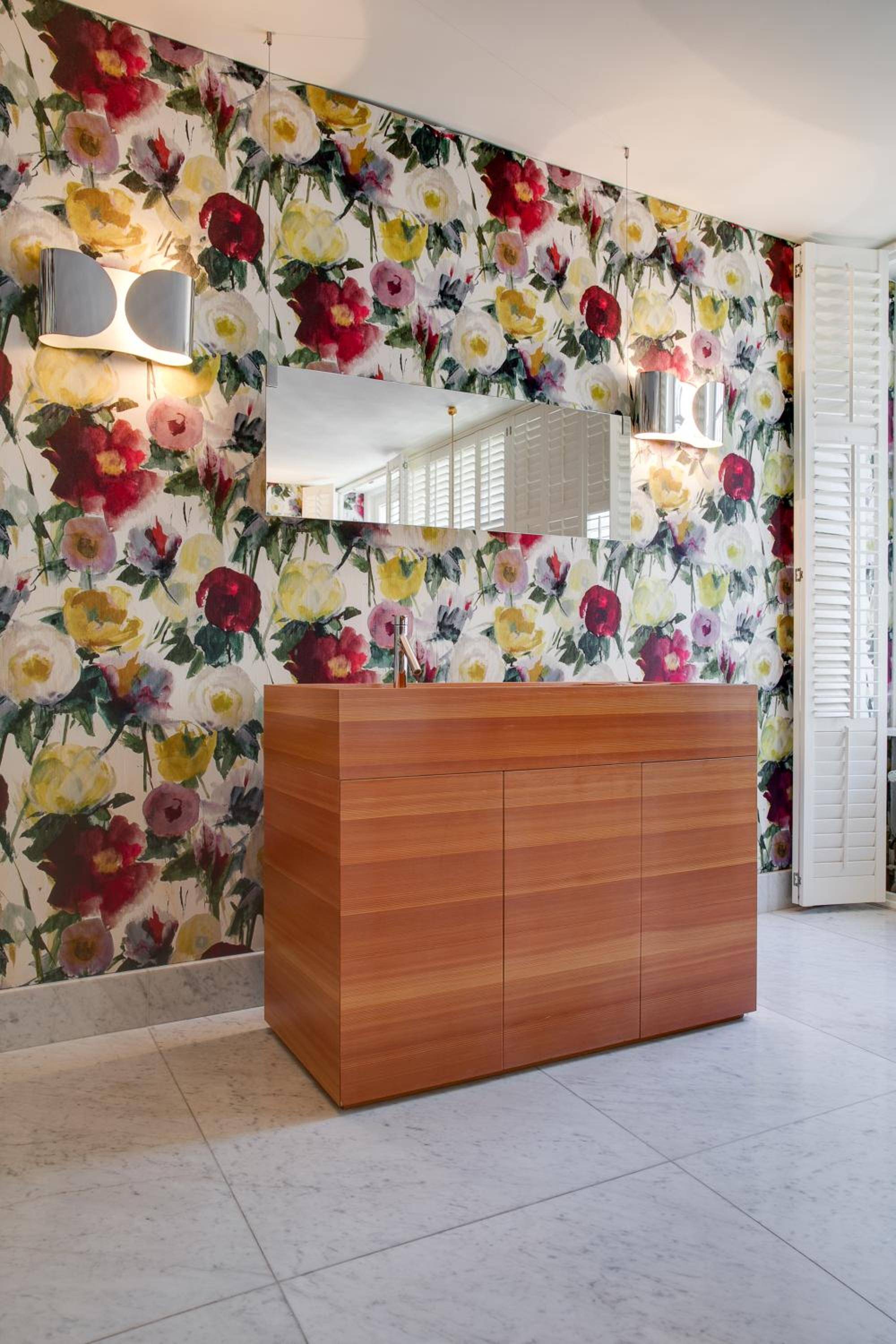 Vibrant floral wallpaper transforms this powder room into an artistic statement, where warm wood cabinetry meets bold botanical blooms in perfect harmony.