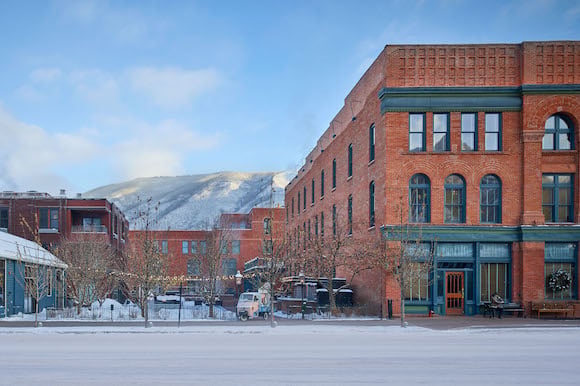 Historic red brick facades frame Aspen's snow-dusted peaks, where Victorian-era architecture meets mountain grandeur in this charming Colorado ski town setting.