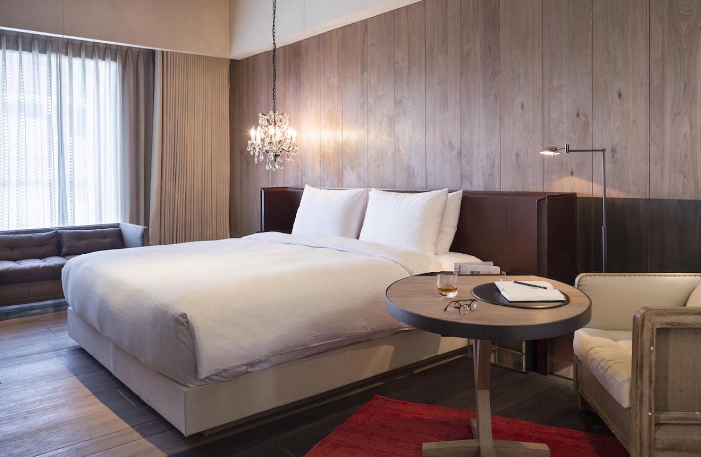 Crystalline chandeliers cast intimate shadows across whitewashed linens while warm wood paneling creates a serene cocoon above the bustling Taipei streets below.
