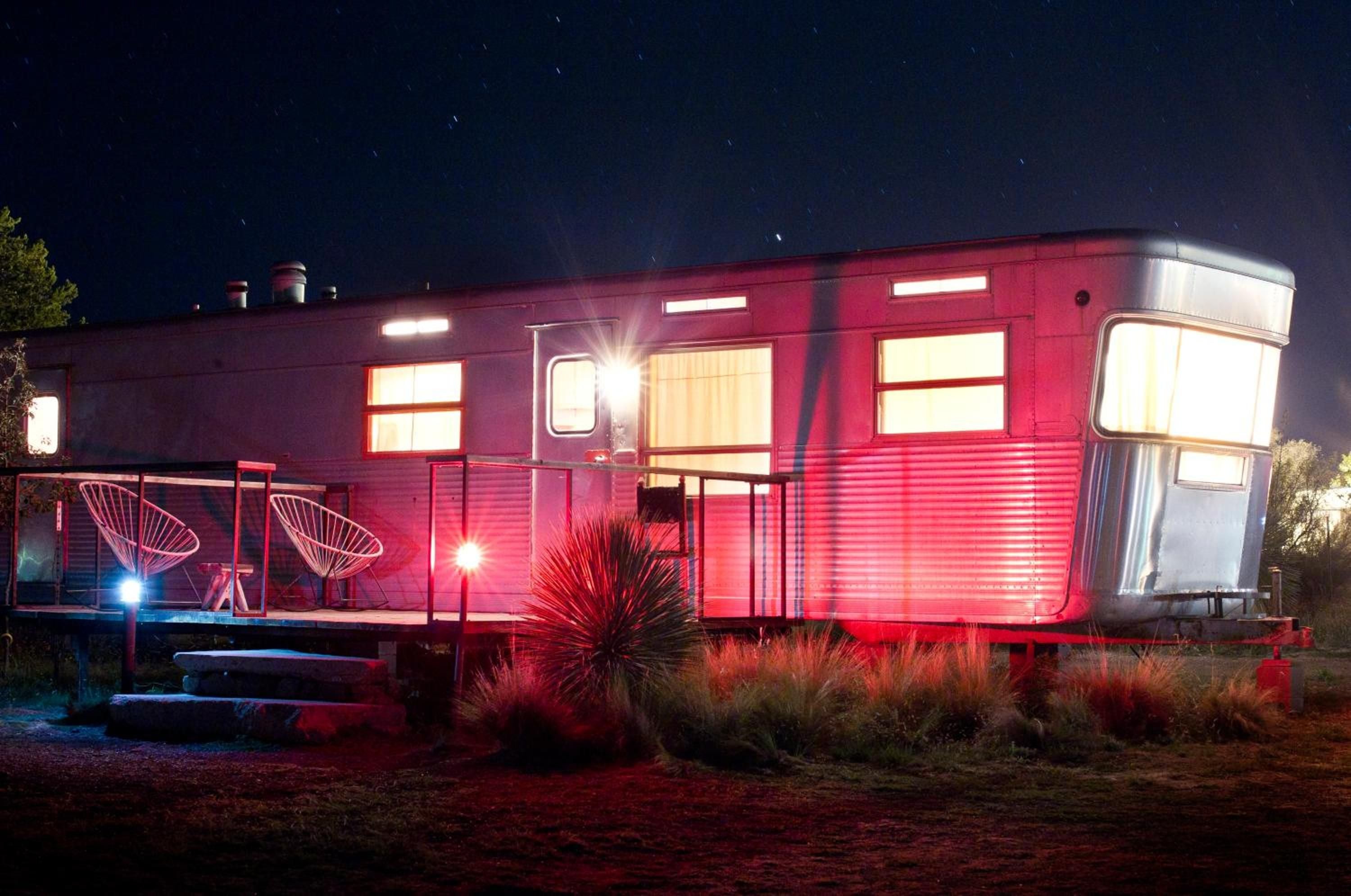 Vintage Airstream trailers glow like lanterns against Marfa's starlit sky, their aluminum curves and warm windows creating an otherworldly desert sanctuary.