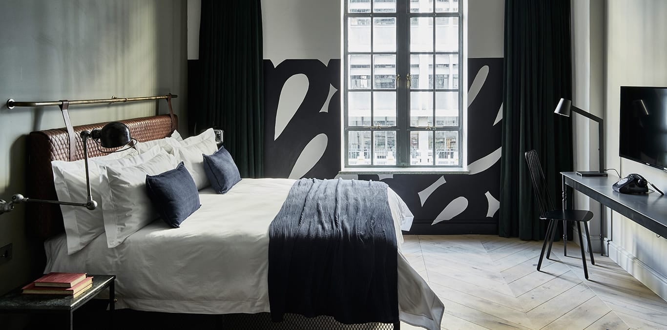 Bold black murals dance across white walls while navy accents and warm wood floors create an intimate sanctuary where industrial meets artisanal in this thoughtfully curated space.