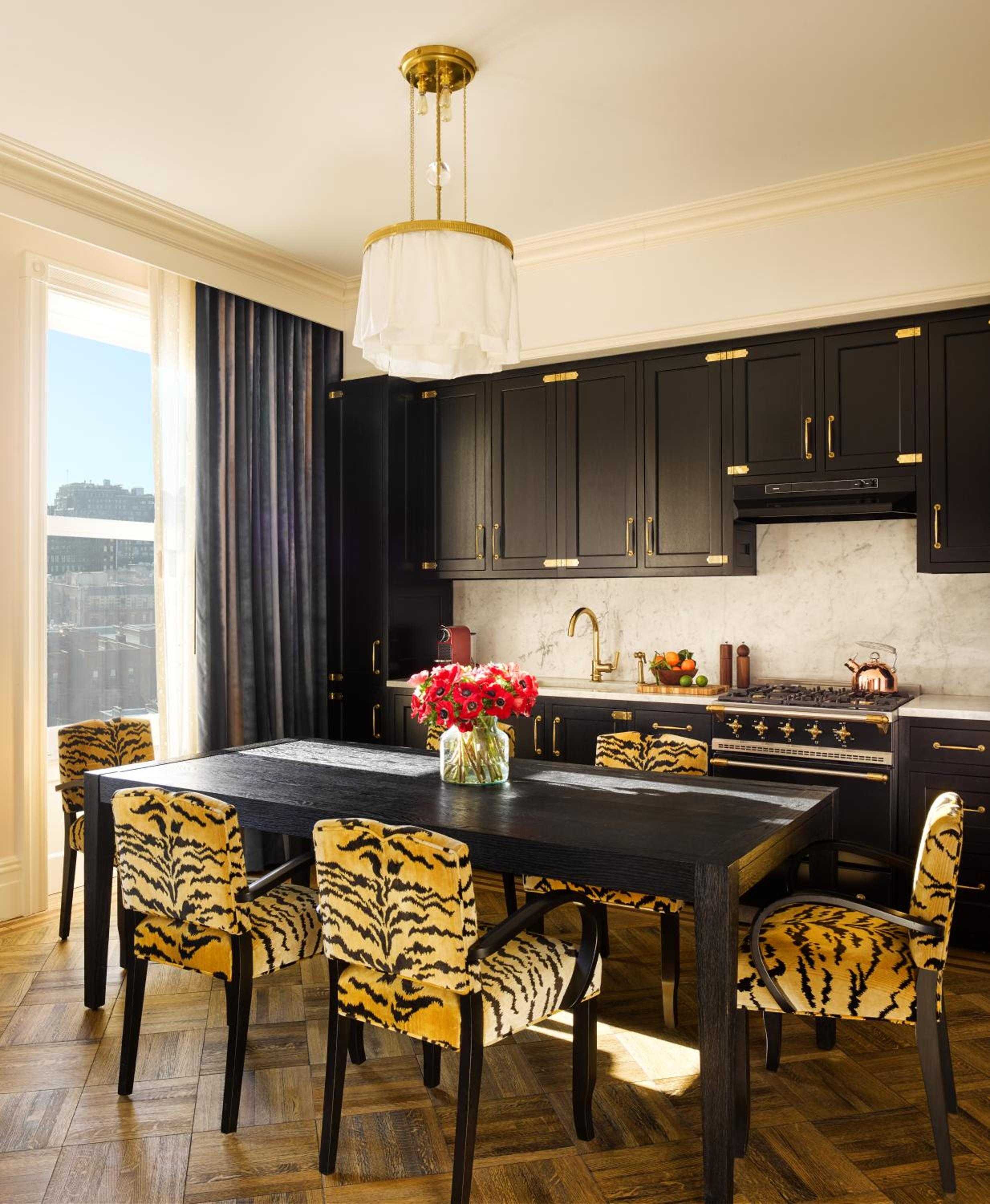 Bold tiger-print chairs and dramatic black cabinetry create an unexpectedly glamorous kitchen where old New York meets contemporary luxury in this thoughtfully appointed suite.