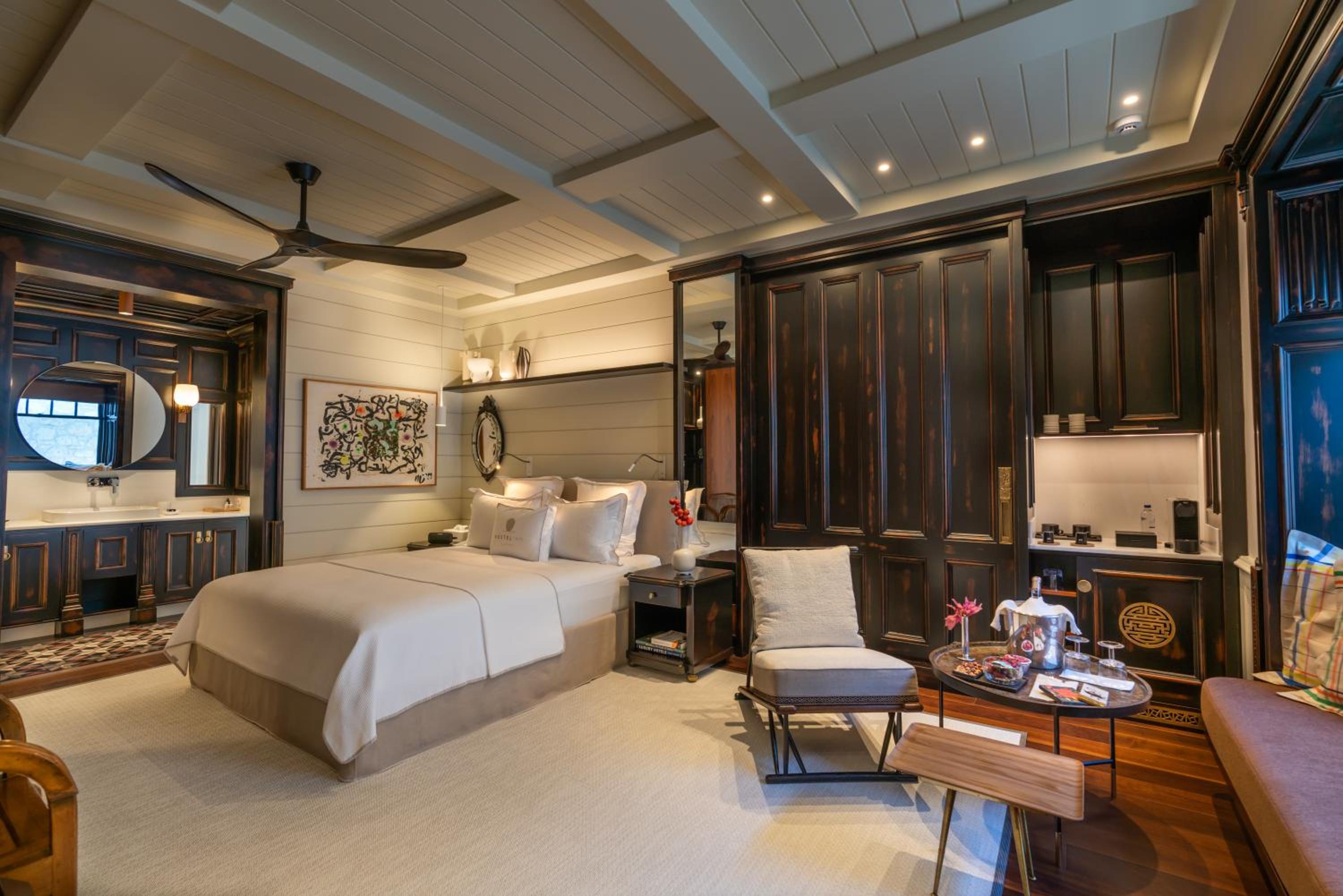 Dark walnut cabinetry and exposed beams create intimate sophistication in this generously appointed suite, where shiplap walls and tailored linens balance rustic charm with refined luxury.