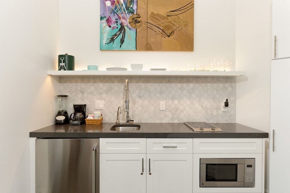Sleek kitchenette showcases marble herringbone backsplash and charcoal countertops, while contemporary artwork adds alpine sophistication to this thoughtfully appointed residential space.