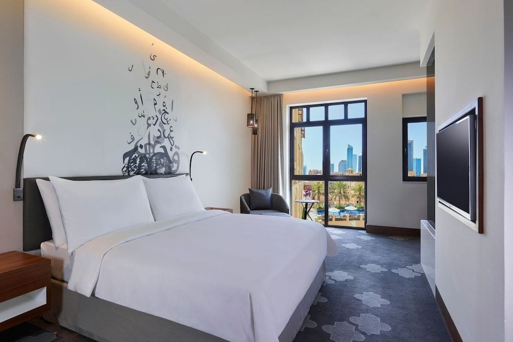 Arabic calligraphy flows across pristine white walls while floor-to-ceiling windows frame Dubai's glittering skyline from this serene sanctuary of modern luxury.