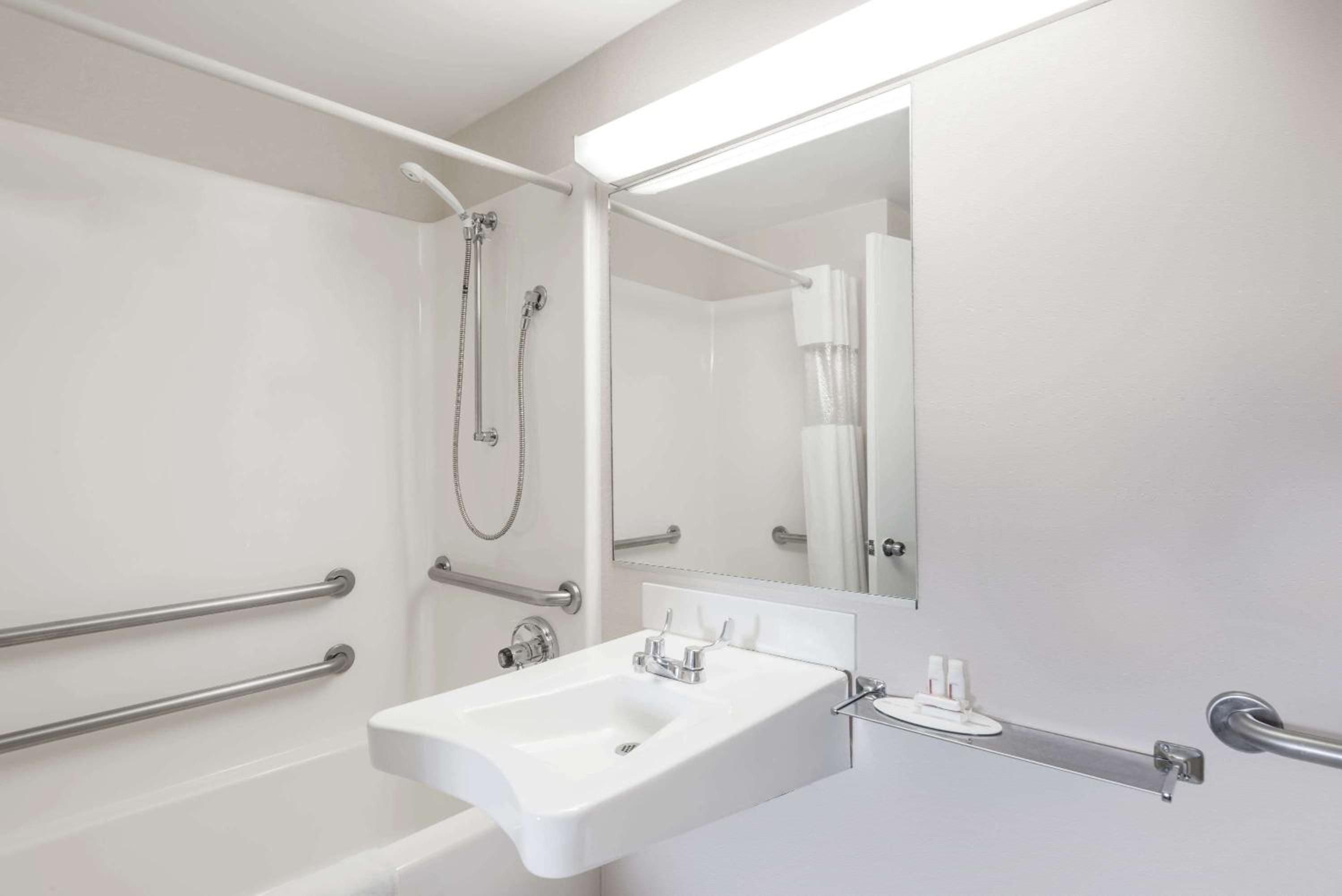 Accessibility meets modern comfort in this thoughtfully designed bathroom, where gleaming grab bars and clean lines create a space that's both practical and inviting.