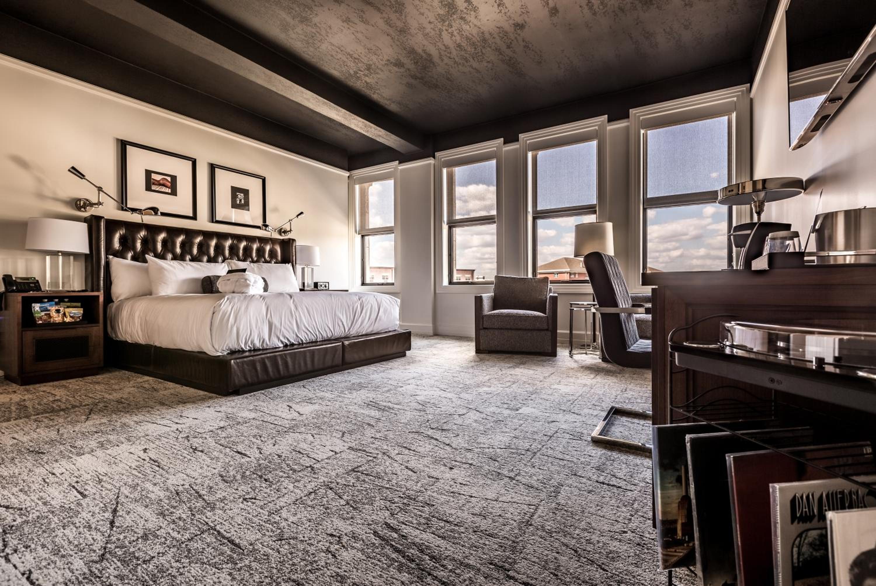 Exposed concrete beams and industrial chic meet refined comfort in this corner suite, where leather tufted headboards frame city views through tall windows.
