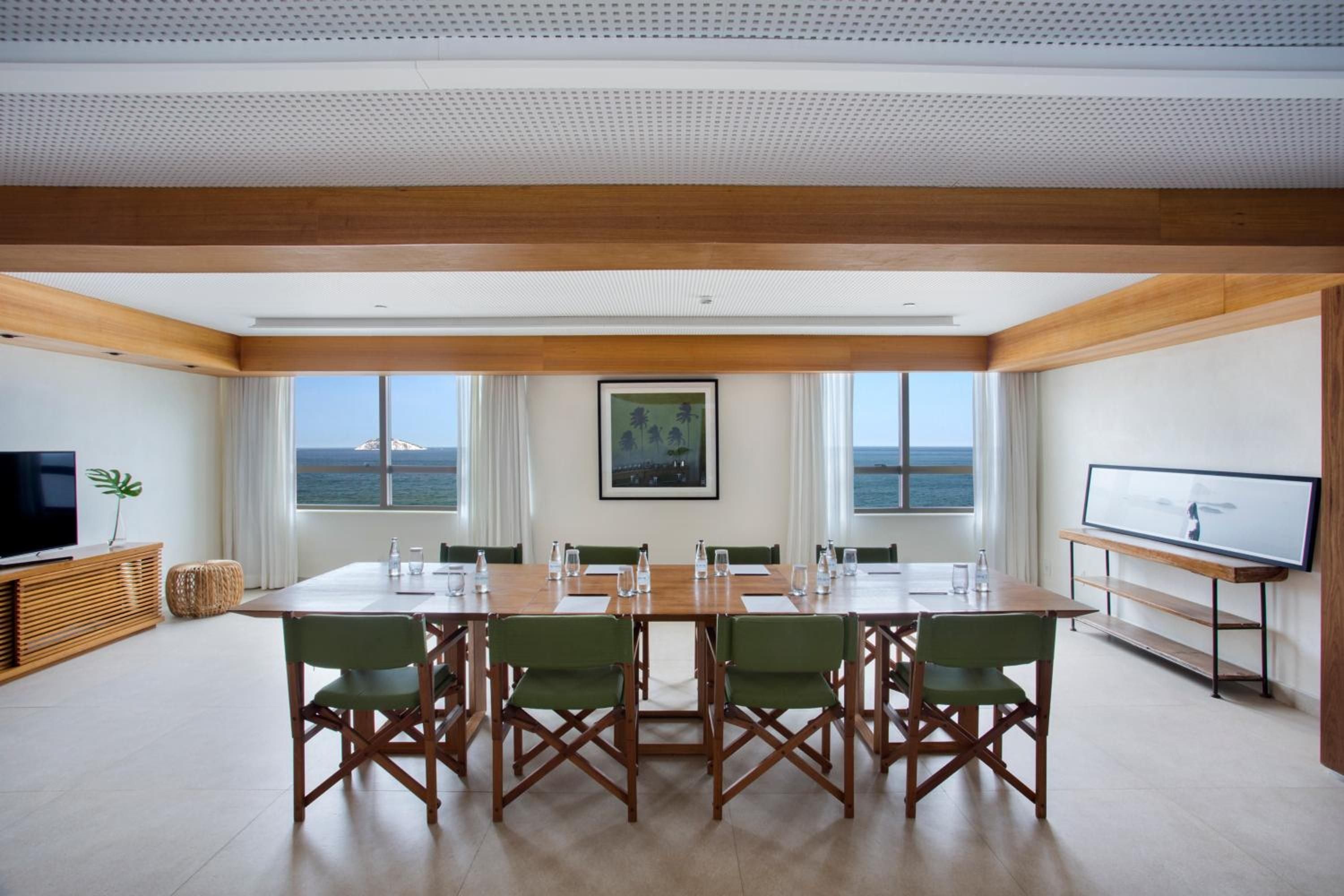Green canvas director's chairs circle a warm wood table in this oceanfront boardroom, where business meetings unfold against endless blue horizons and natural light.
