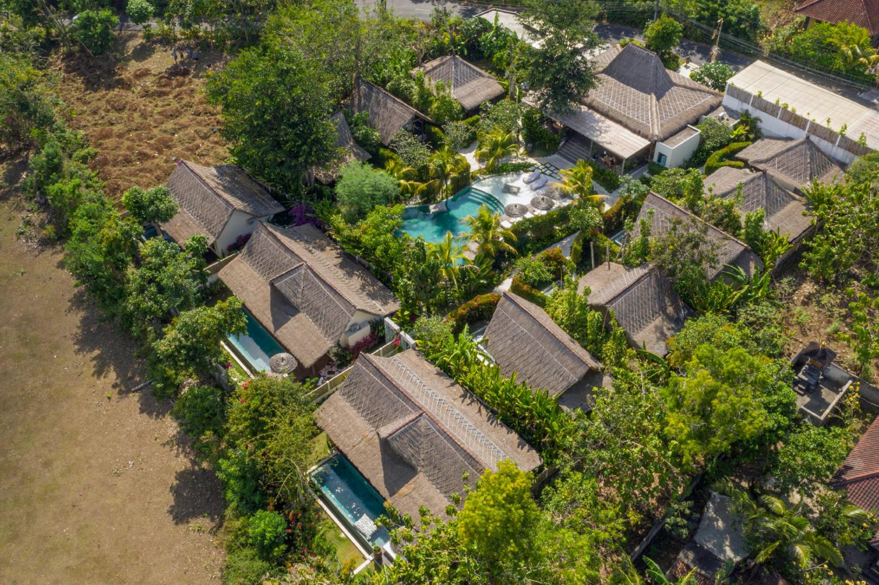 Traditional thatched-roof villas cluster around azure pools like a Balinese village, where lush tropical gardens blur the boundaries between luxury and authentic island living.
