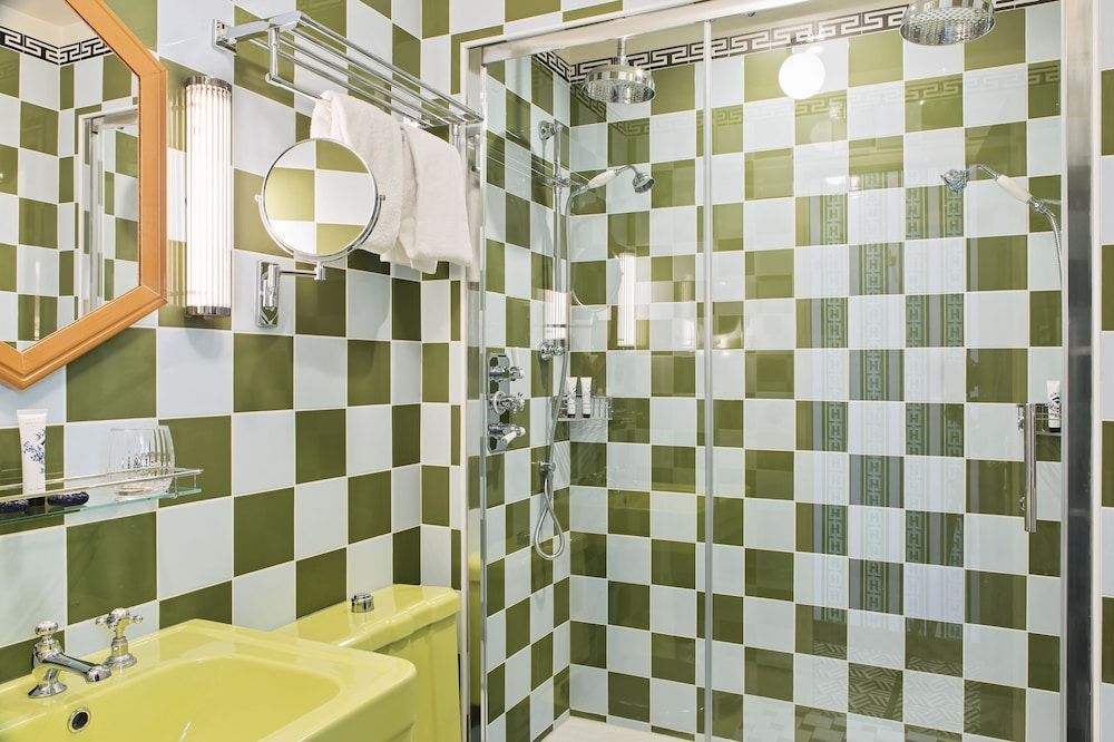Bold green and white checkerboard tiles create a playful yet sophisticated bathroom atmosphere, complemented by gleaming chrome fixtures and thoughtful lighting that reflects off polished surfaces.