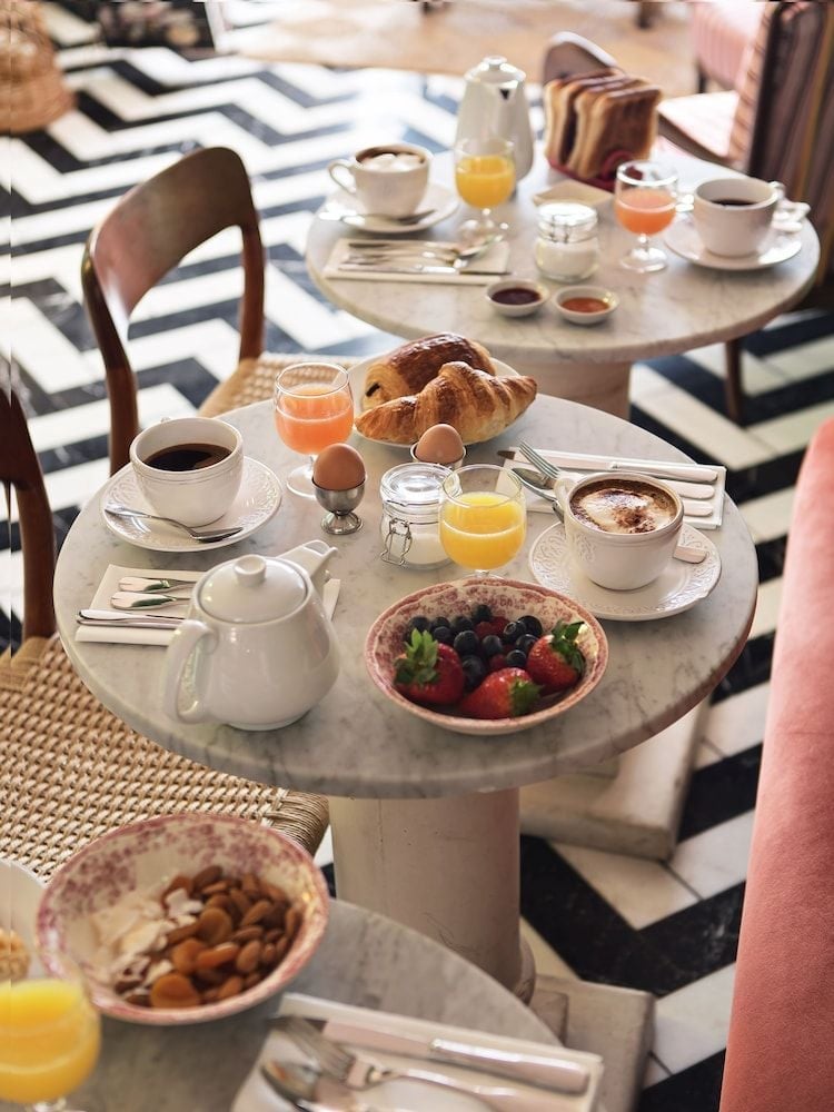 Morning light streams across marble bistro tables where fresh croissants, seasonal berries, and perfectly brewed coffee create an intimate Parisian breakfast ritual.