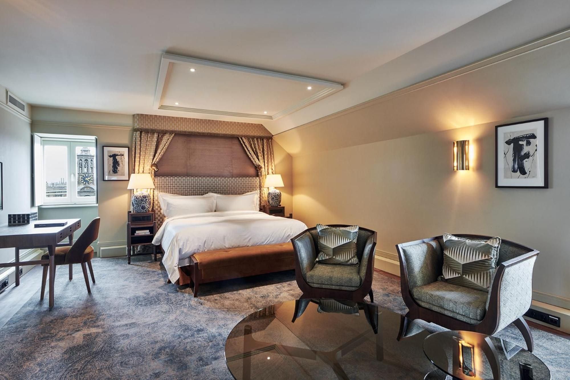Plush velvet armchairs and an ornate canopy bed create an atmosphere of refined elegance in this sophisticated suite overlooking Amsterdam's historic canals.