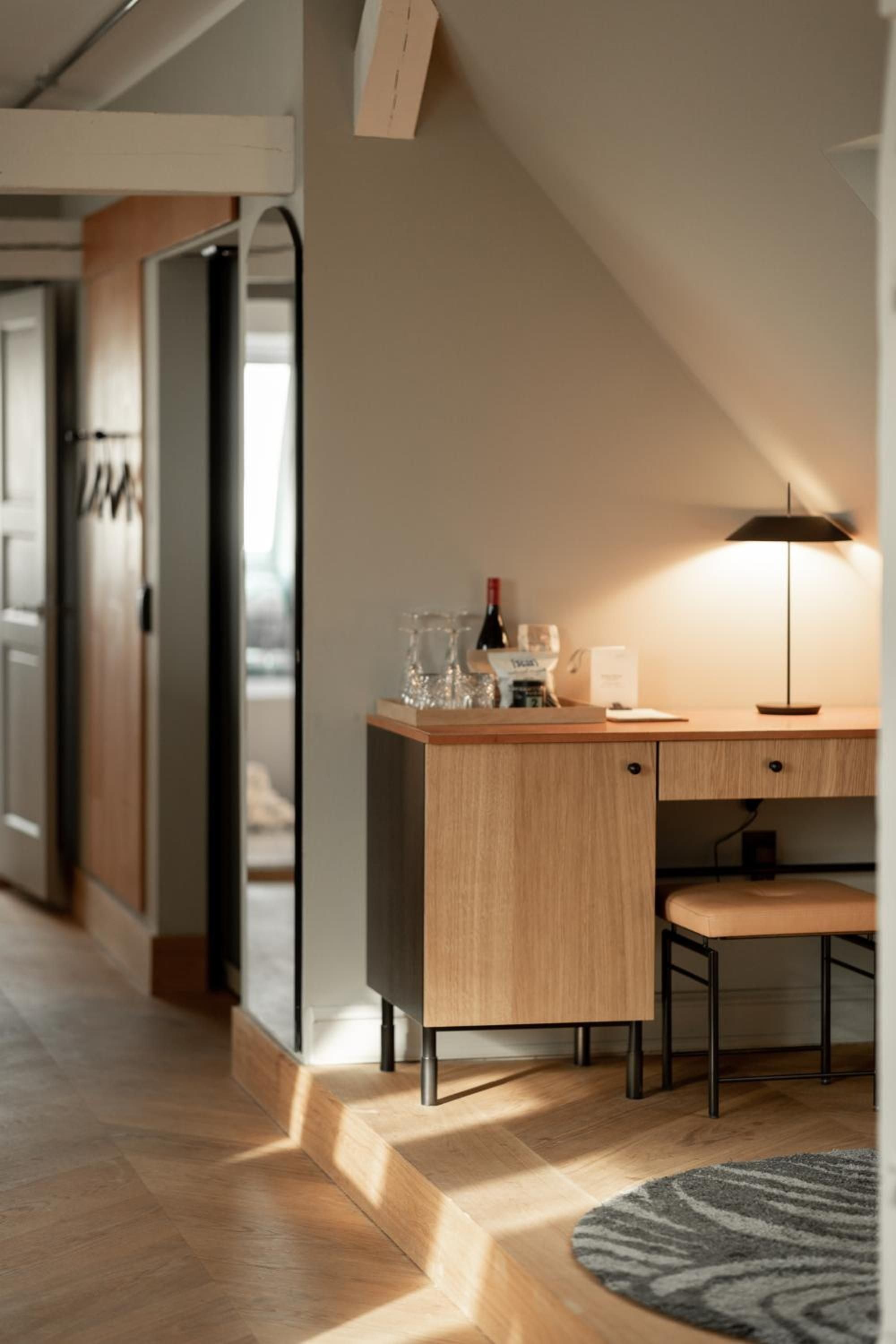 Warm wood tones and Danish design sensibility create intimate corners where natural light dances across herringbone floors beneath slanted attic ceilings.