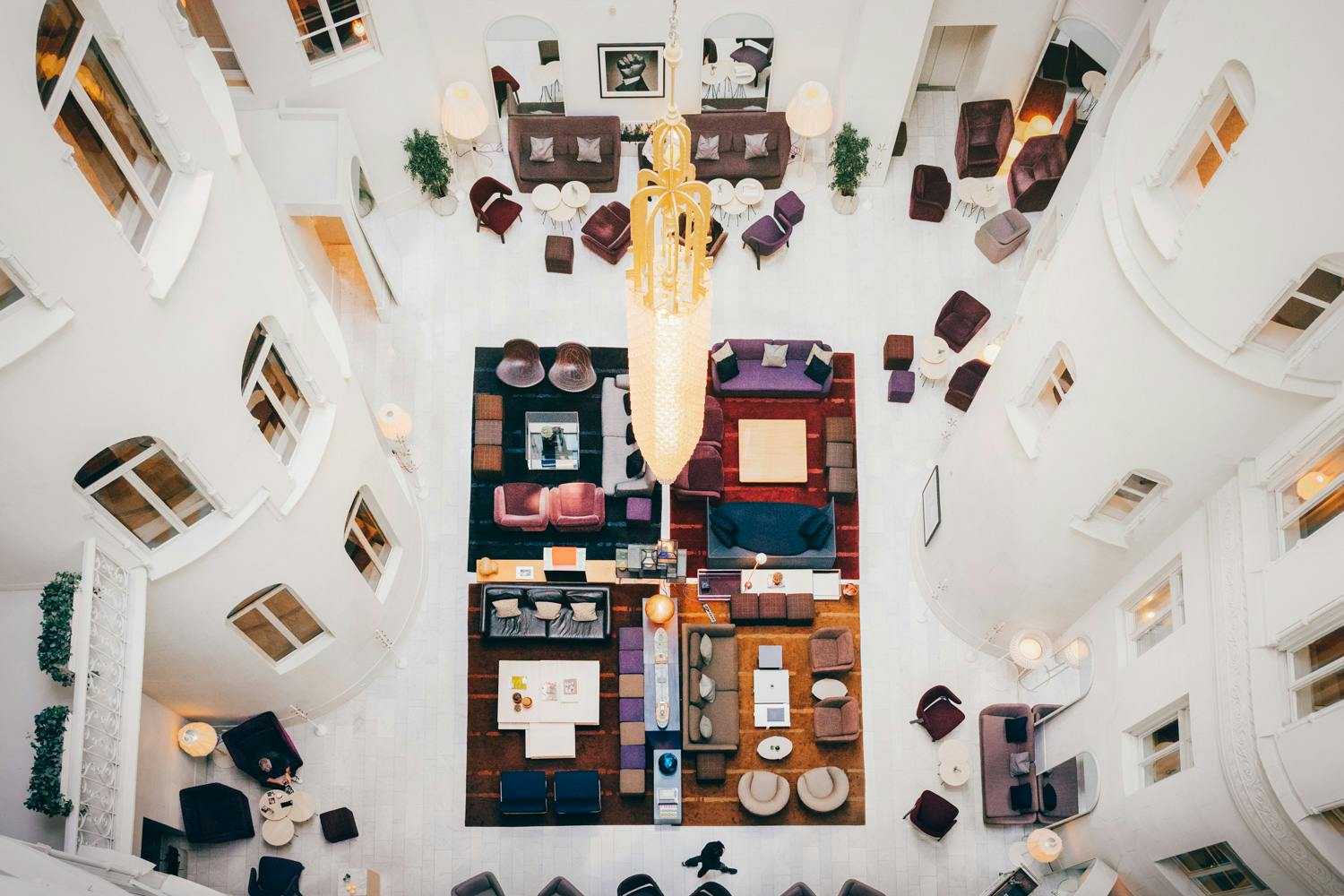 Soaring above Stockholm's most stylish lobby reveals a carefully curated patchwork of jewel-toned seating, warm wood floors, and that show-stopping golden chandelier commanding the marble atrium.