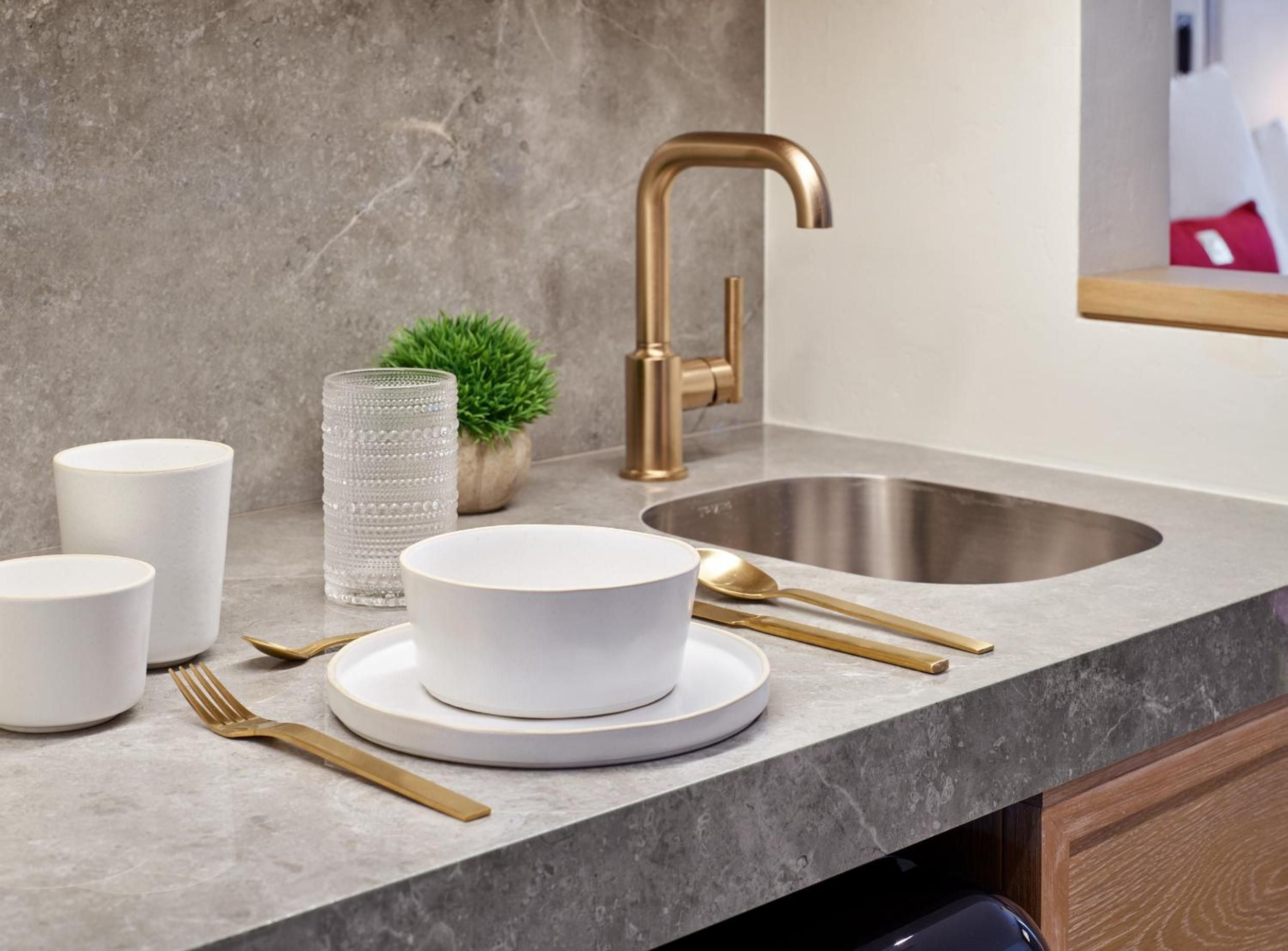 Brass fixtures and marble countertops create sophisticated mountain luxury, where gold-toned cutlery and pristine white ceramics reflect Aspen's refined alpine aesthetic.