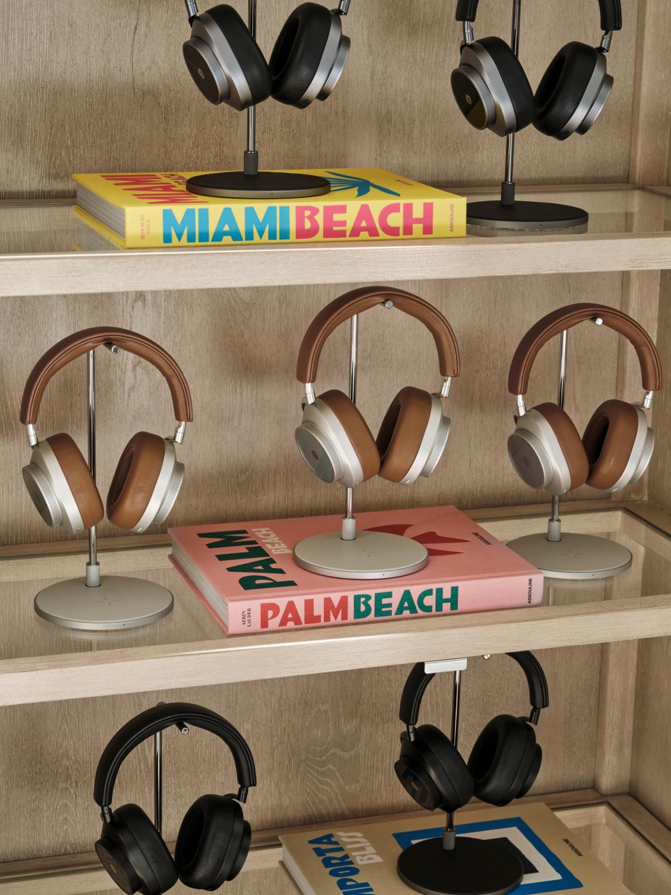 Sleek headphone displays on warm wood shelving create an unexpectedly modern tech corner, where colorful Miami and Palm Beach coffee table books add coastal flair.