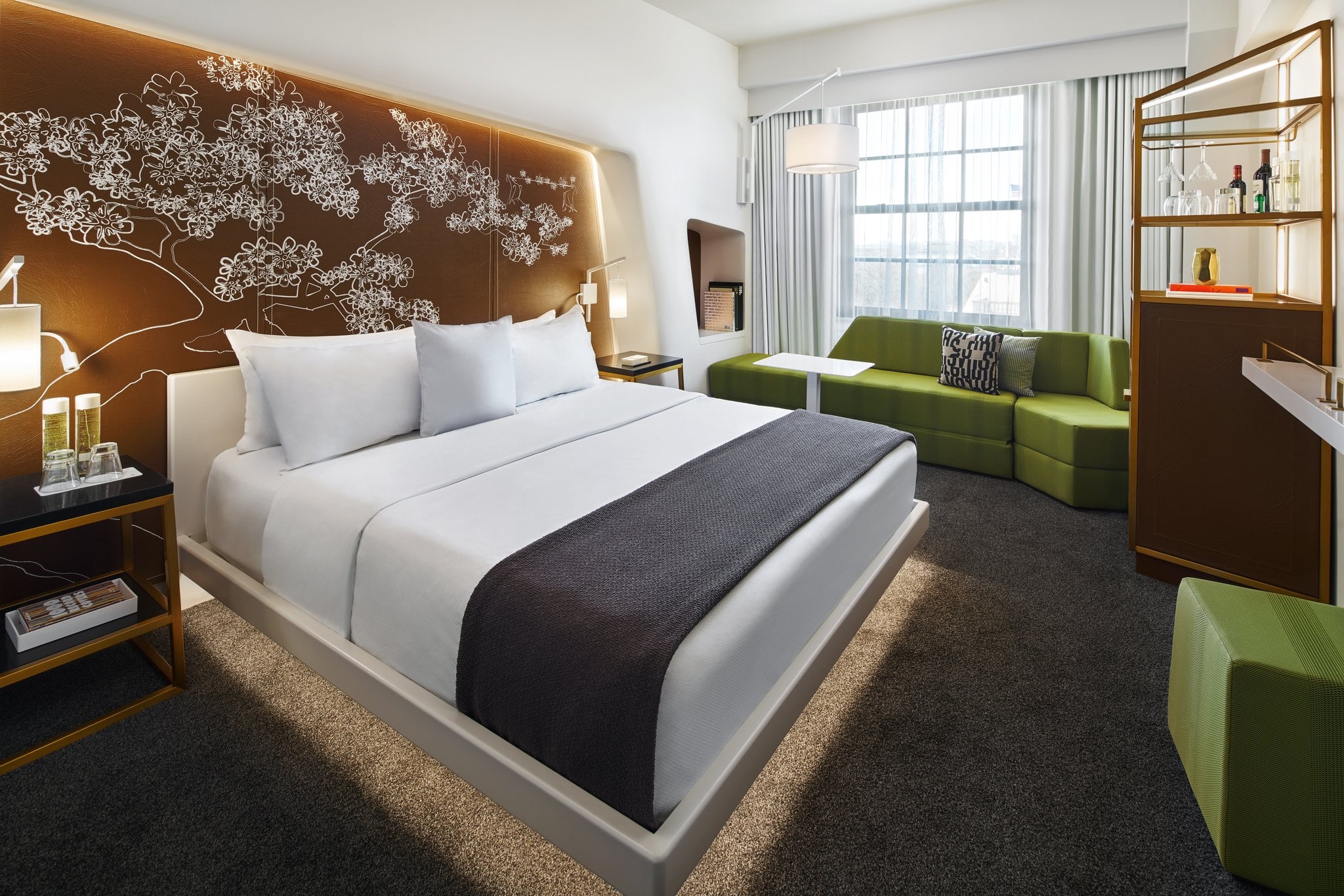 Crisp white linens contrast beautifully against the dramatic tree-motif headboard, while lime-green seating adds unexpected vibrancy to this thoughtfully designed guest room.