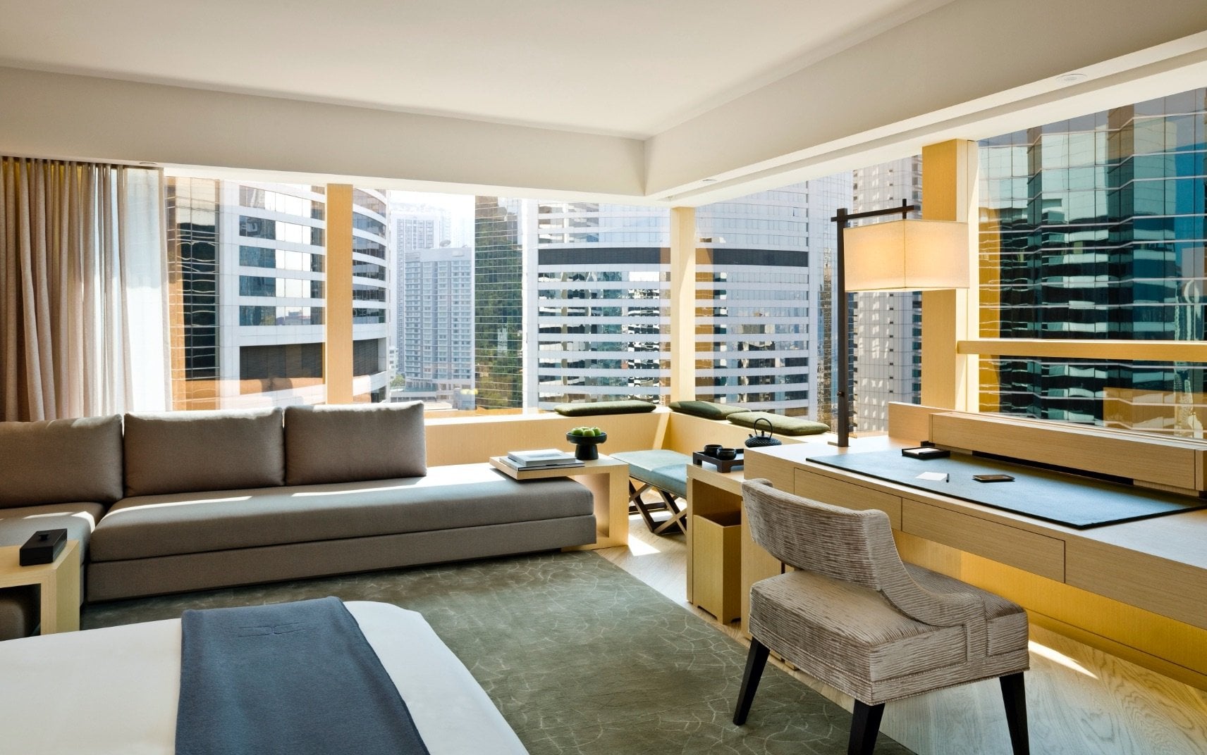 Floor-to-ceiling windows frame Hong Kong's glittering towers from this sophisticated suite, where honey-toned wood and grey furnishings create serene counterpoint to the urban energy beyond.
