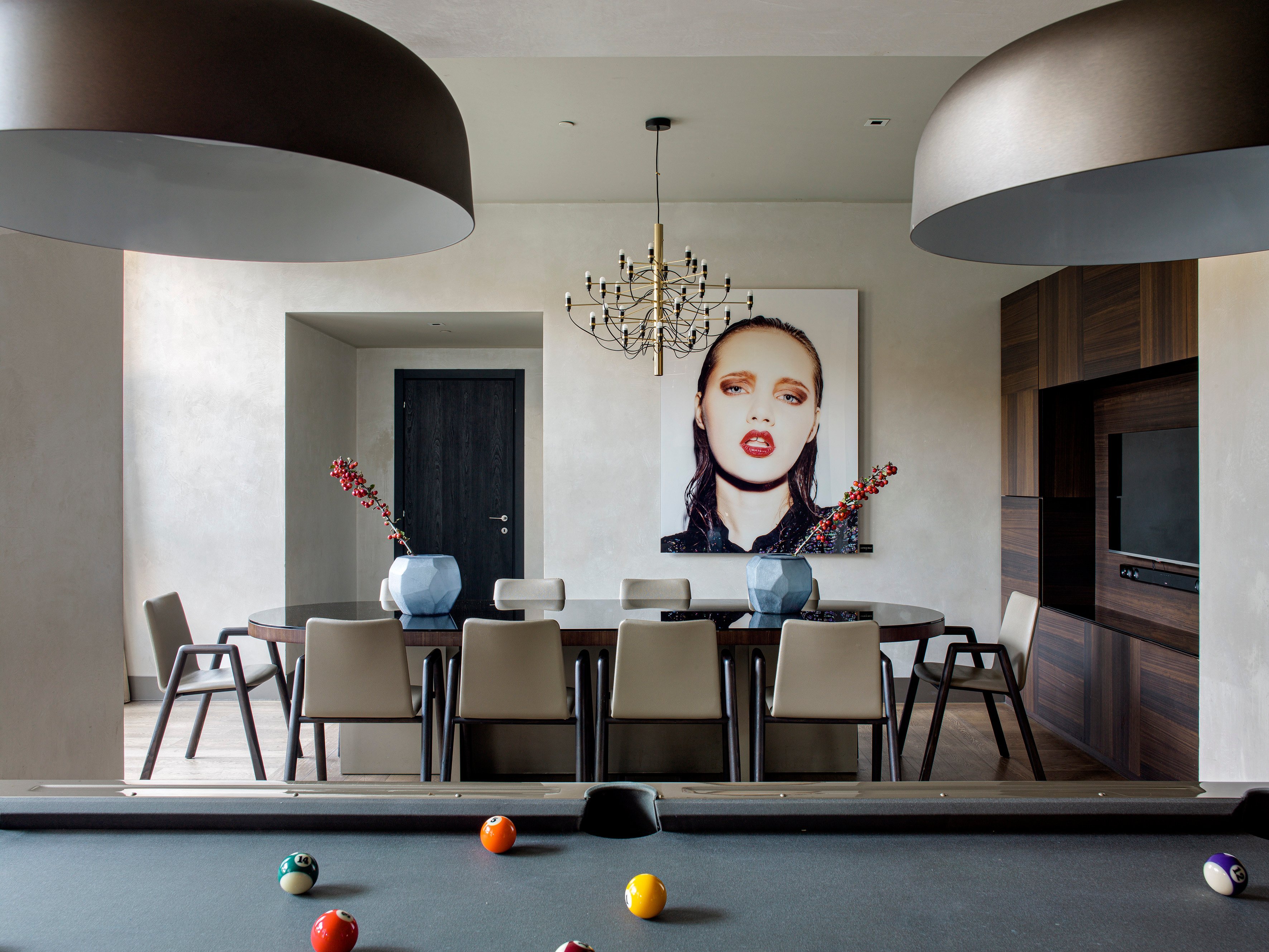 Contemporary art commands attention in this sleek dining space where oversized pendant lights frame intimate conversations and billiard balls hint at after-dinner entertainment.