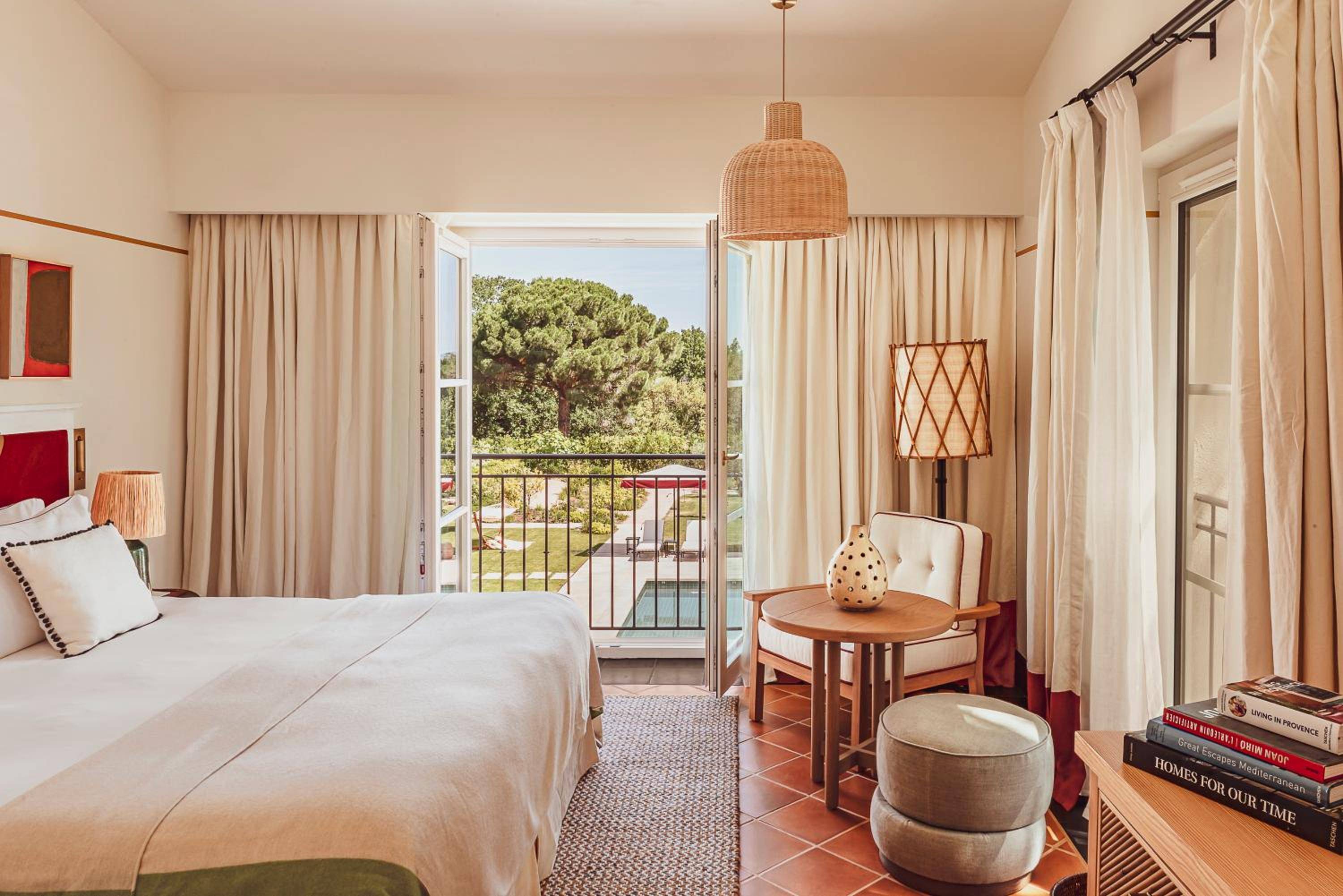 Wicker pendant lights cast gentle shadows across terracotta floors while French doors frame pine-studded landscapes beyond the private balcony's iron railings.